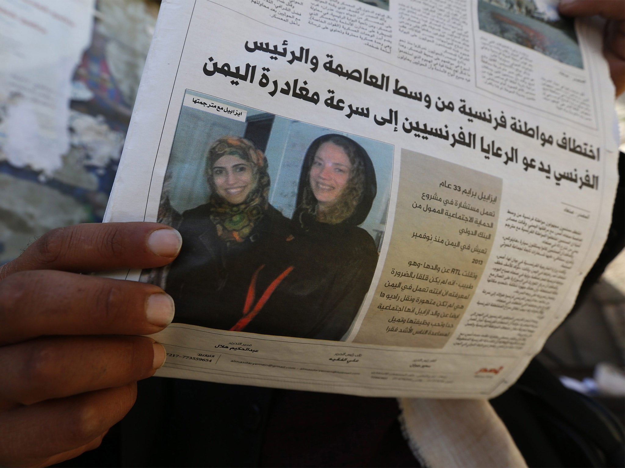 A Yemeni man reads a local newspaper publishing a photograph of kidnapped French aid worker Isabelle Prime (right) and her Yemeni colleague Shireen Makkauy