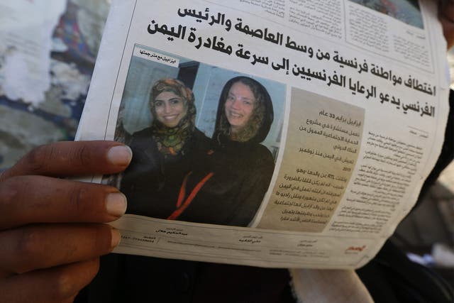 A Yemeni man reads a local newspaper publishing a photograph of kidnapped French aid worker Isabelle Prime (right) and her Yemeni colleague Shireen Makkauy