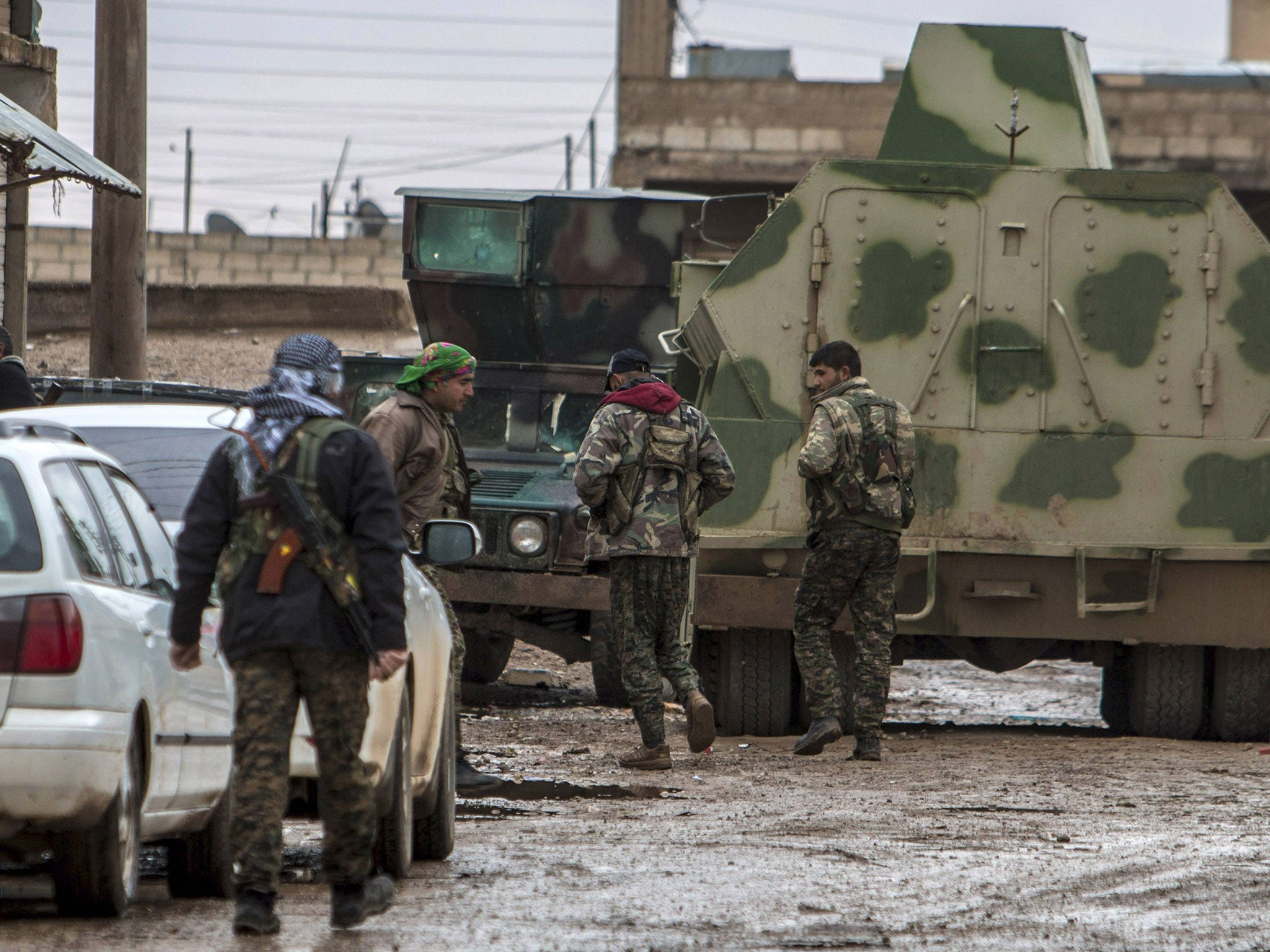 Fighters of the Kurdish People's Protection Units (YPG) walk past an armored vehicle along a street in the town of Tel Tamr February 25, 2015