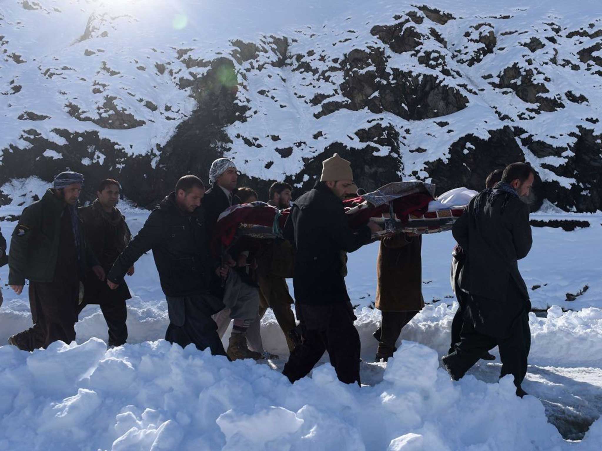 Afghan men carry the body of a victim of avalanches after funeral prayers in Khench district of Panjshir province