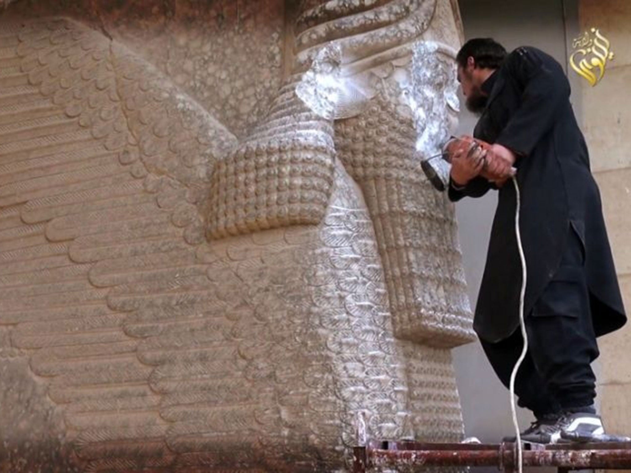 An image grab taken off a video reportedly released by Media Office of the Nineveh branch of the Islamic State (IS) Group on February 25, 2015, allegedly shows an IS militant destroying the statue of Lamassu, an Assyrian diety, with a jackhammer in the northern Iraqi Governorate of Nineveh.