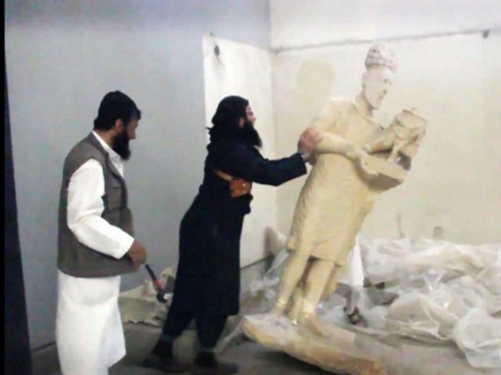 An image grab taken off a video reportedly released by Media Office of the Nineveh branch of the Islamic State (IS) Group on February 25, 2015, allegedly shows an IS militant pushing a statue inside the Mosul museum in the northern Iraqi Governorate of Ni