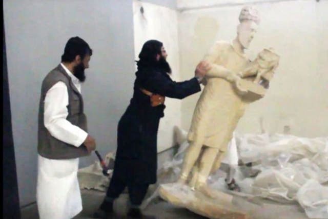An image grab taken off a video reportedly released by Media Office of the Nineveh branch of the Islamic State (IS) Group on February 25, 2015, allegedly shows an IS militant pushing a statue inside the Mosul museum in the northern Iraqi Governorate of Ni