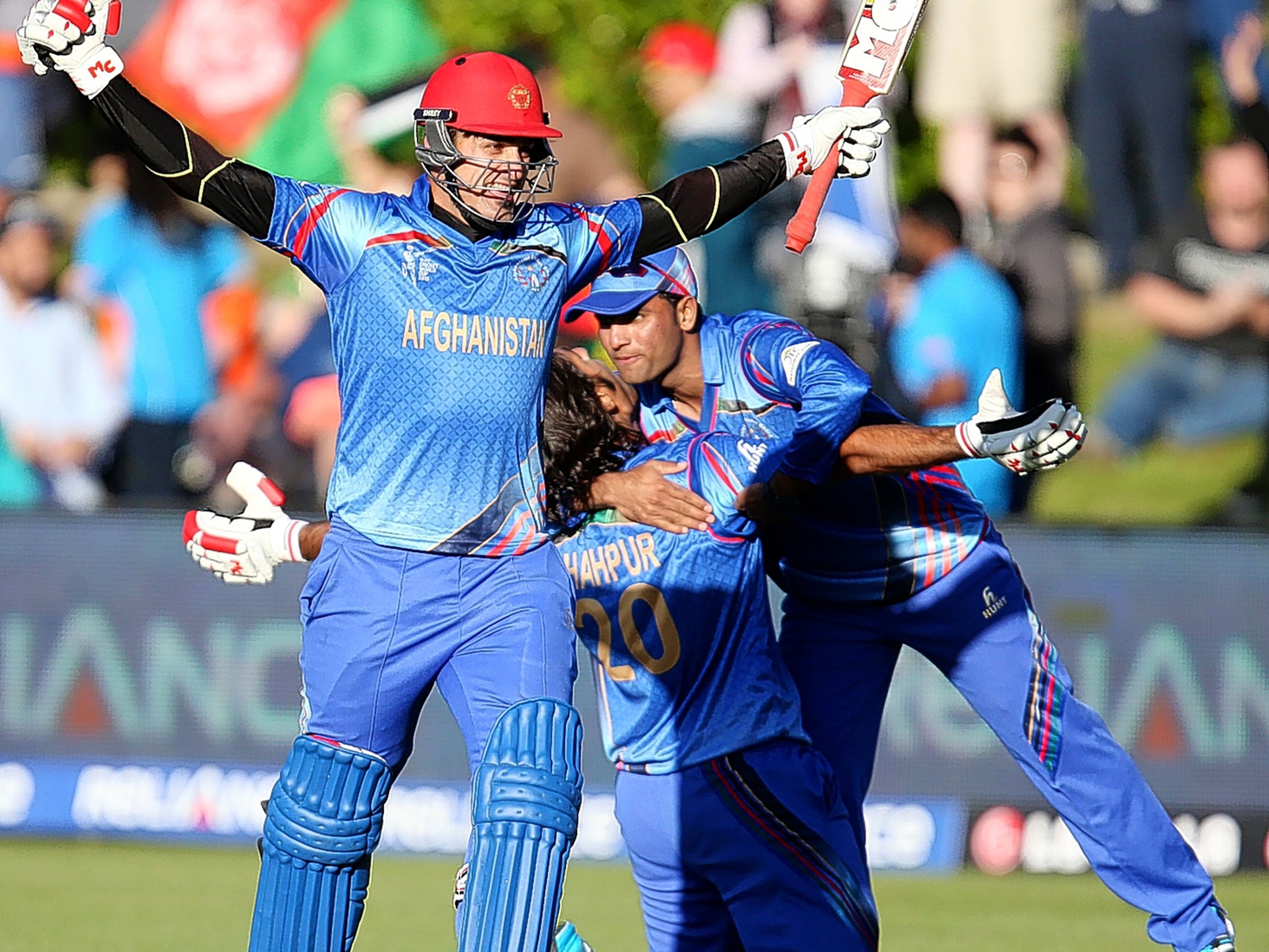 Afghanistan’s Hamid Hassan raises his bat in celebration after their World Cup win over Scotland in Dunedin