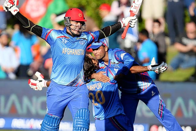 Afghanistan’s Hamid Hassan raises his bat in celebration after their World Cup  win over Scotland in Dunedin