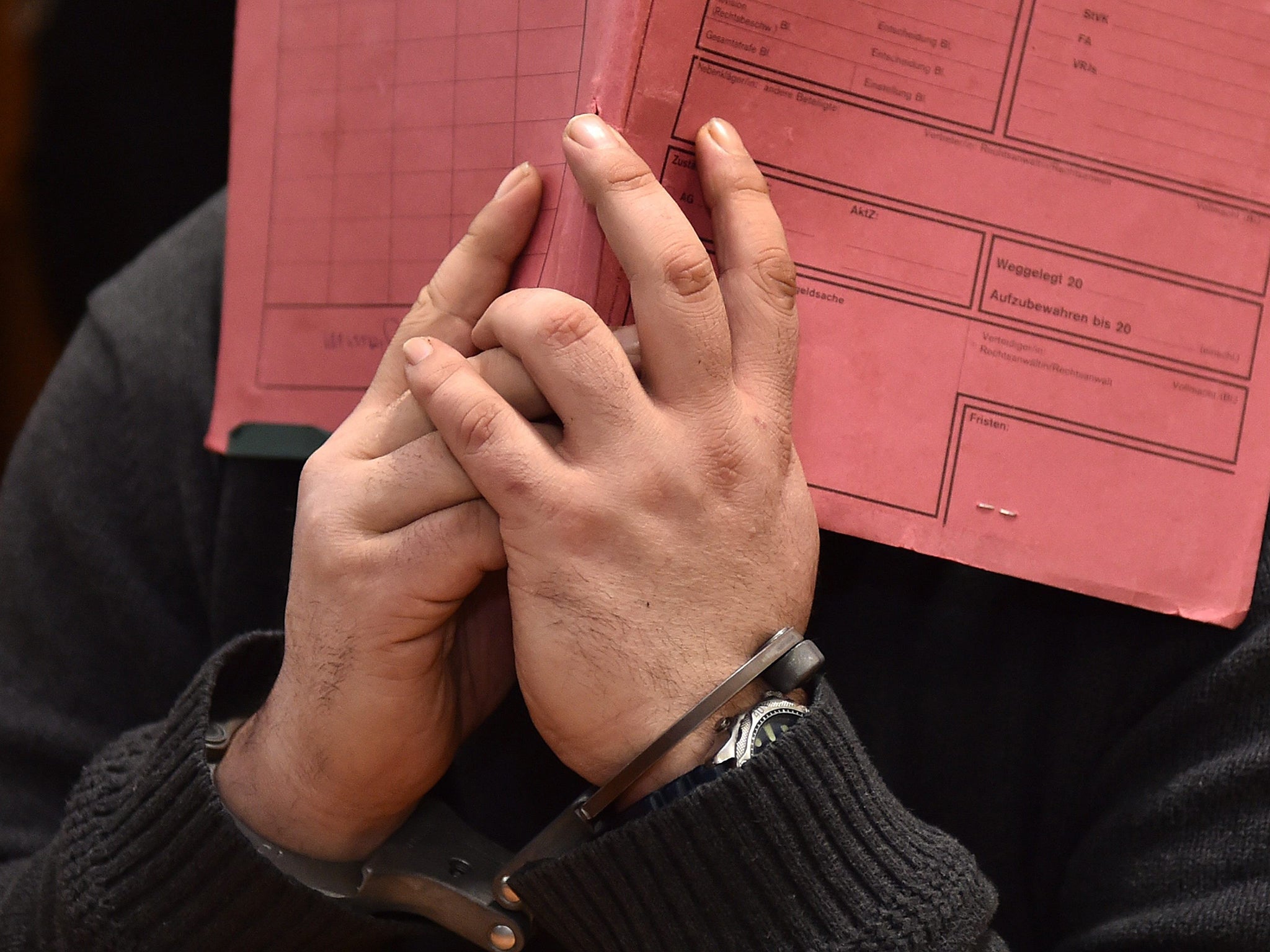 Former nurse Niels H. hiding his face behind a folder during his trial in Oldenburg, Lower Saxony, Germany,