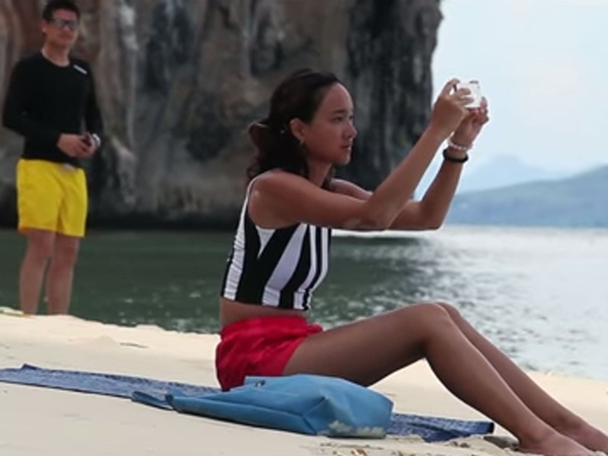 A man follows a woman onto a Thai beach without her realising