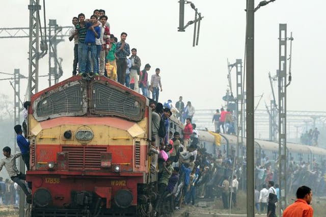 Passengers stand and hang on to a train as it departs New Delhi last week. The latest budget promises higher investment in the railway