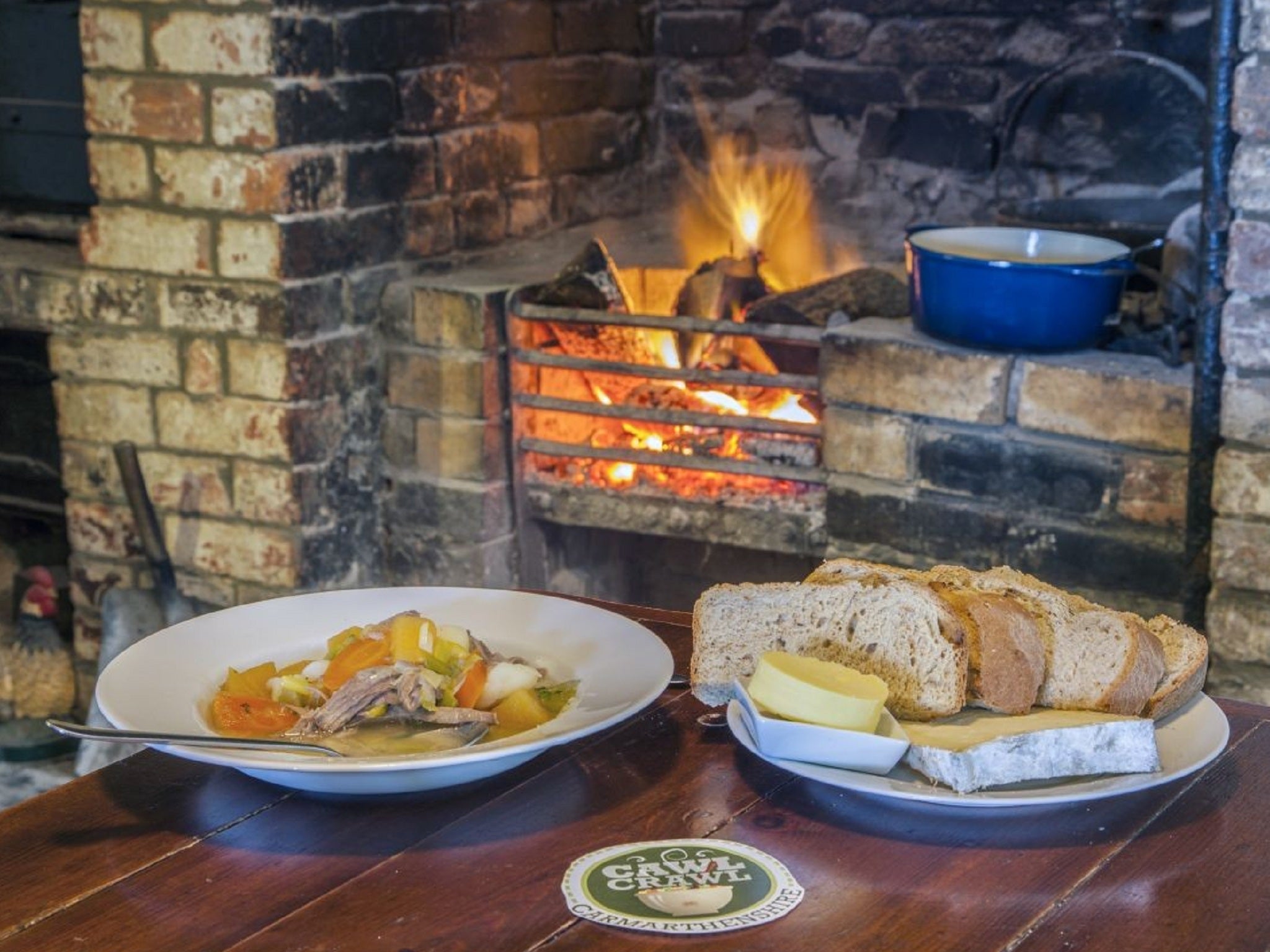 A warming bowl of cawl goes well with servings of bread in front of a fire