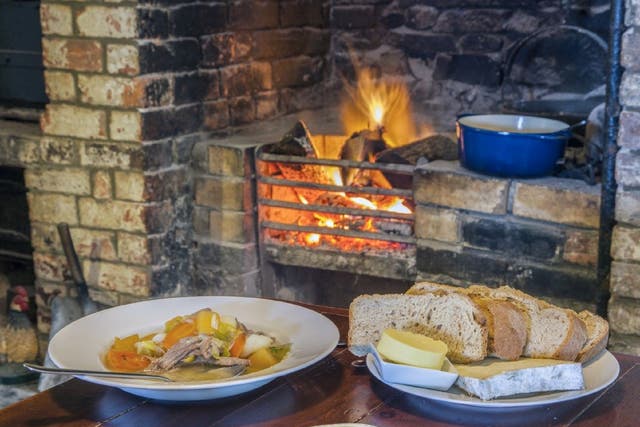 A warming bowl of cawl goes well with servings of bread in front of a fire