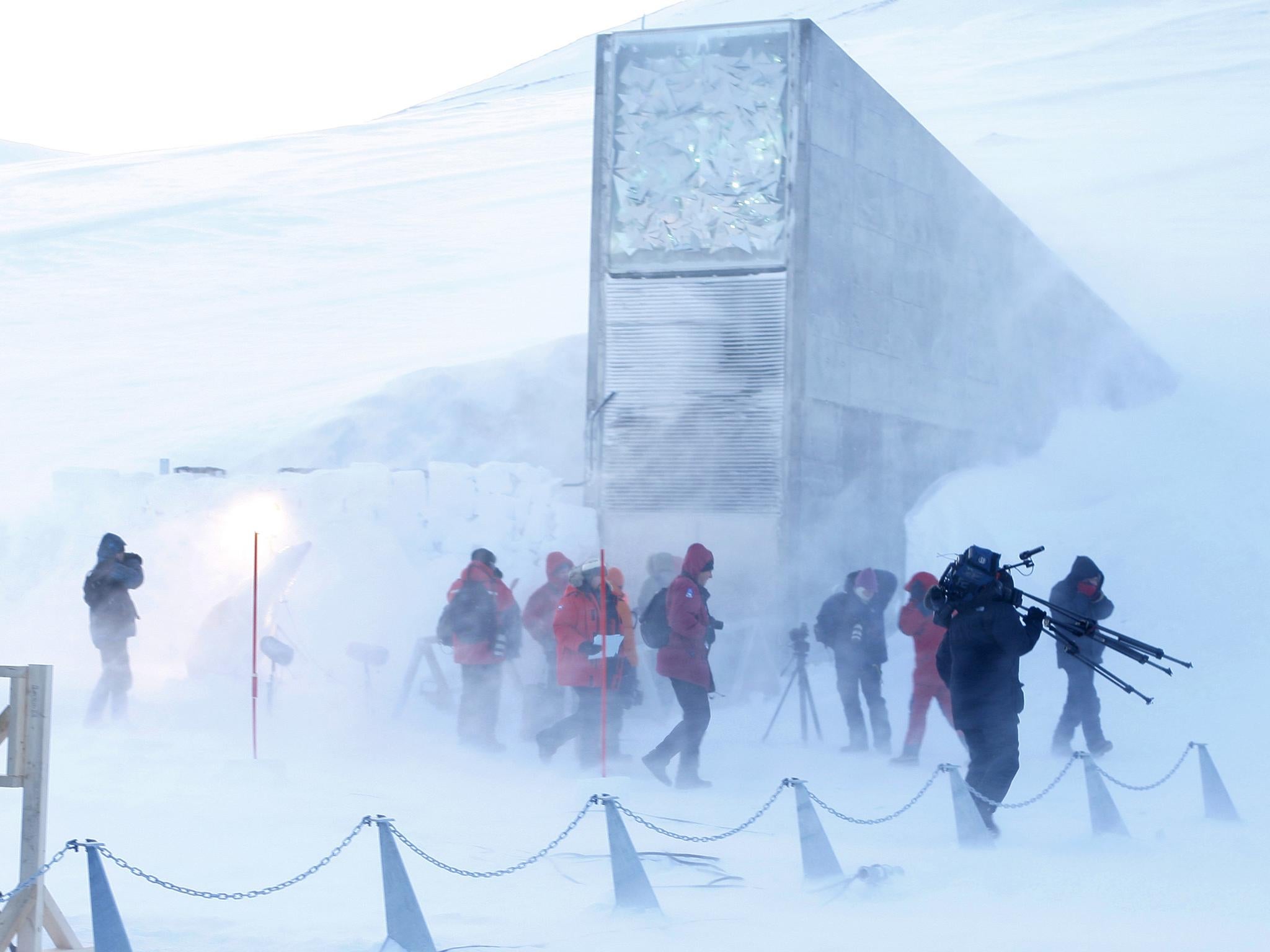 Journalists and cameramen walk under a gust of cold wind near the entrance of the Svalbard Global Seed Vault that was officially opened near Longyearbyen on February 26, 2008
