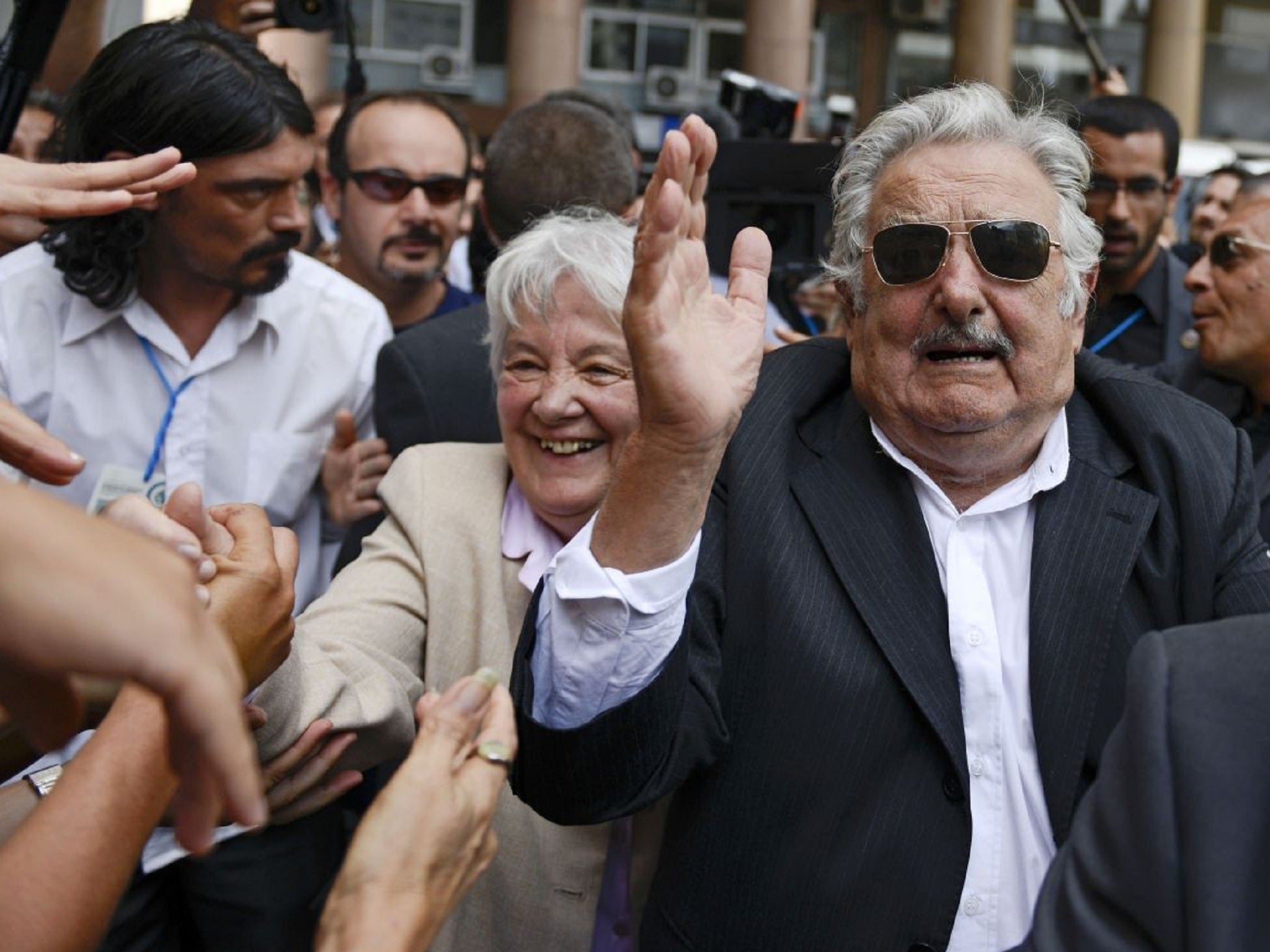 Jose Mujica with his wife being applauded and cheered on by crowds in Uruguay