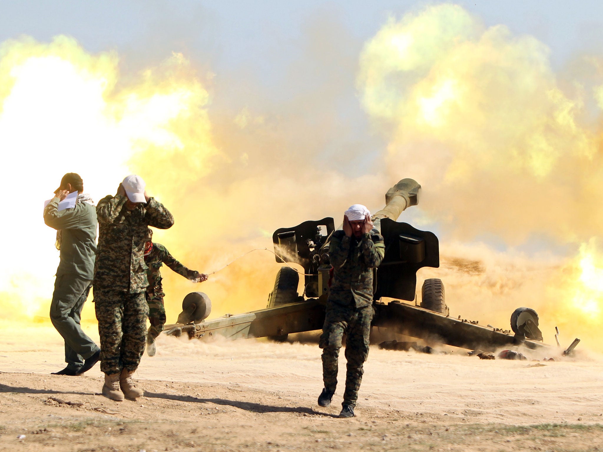 Volunteer Shiite fighters, known as the Popular Mobilisation units, who support the Iraqi government forces in the combat against the Islamic State (IS) group fire a Howitzer artillery canon in the village of Awaynat near the city of Tikrit