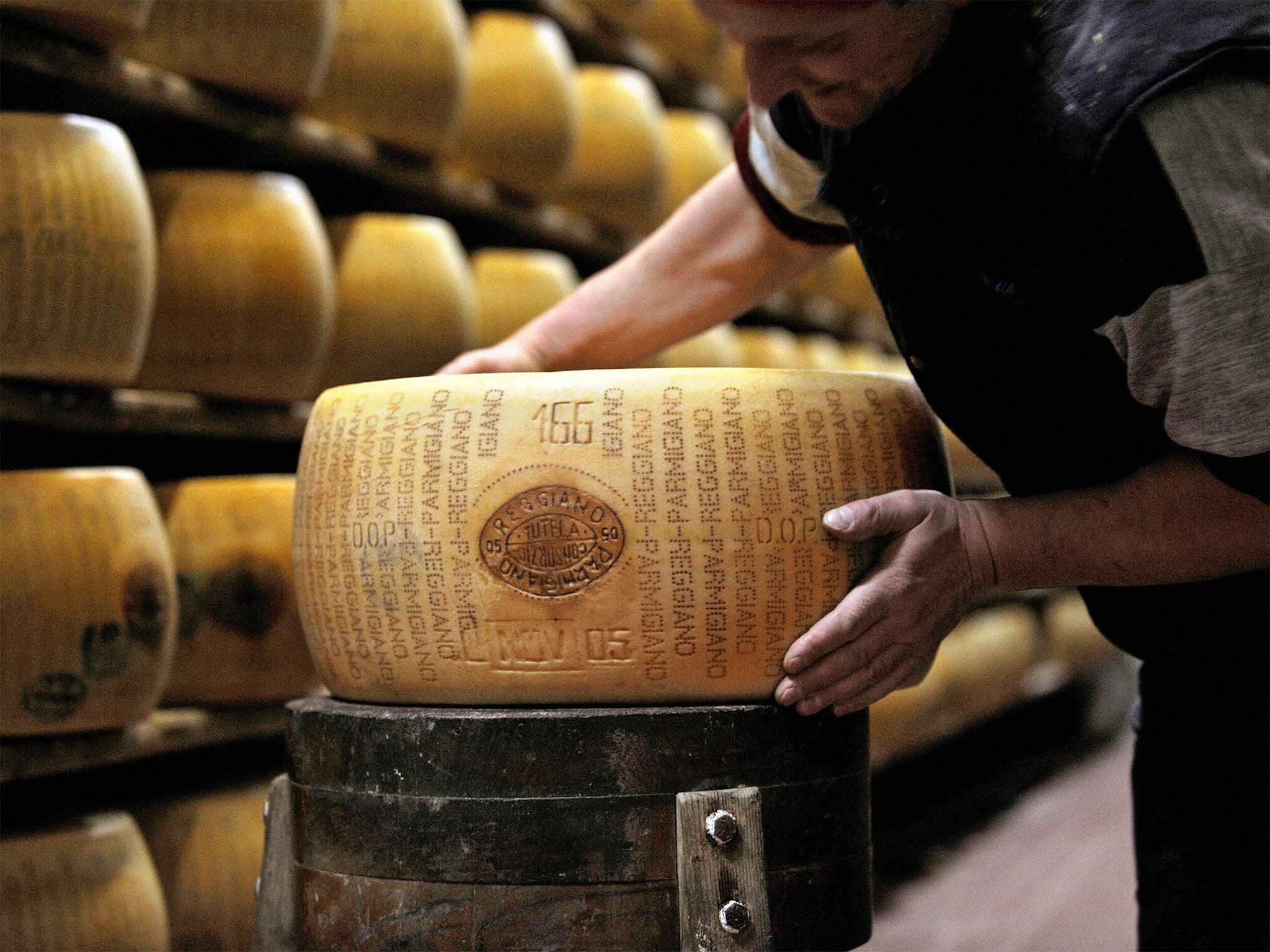 A worker checking a wheel of seasoned Parmigiano Reggiano cheese in a factory in Valestra, near Bologna
