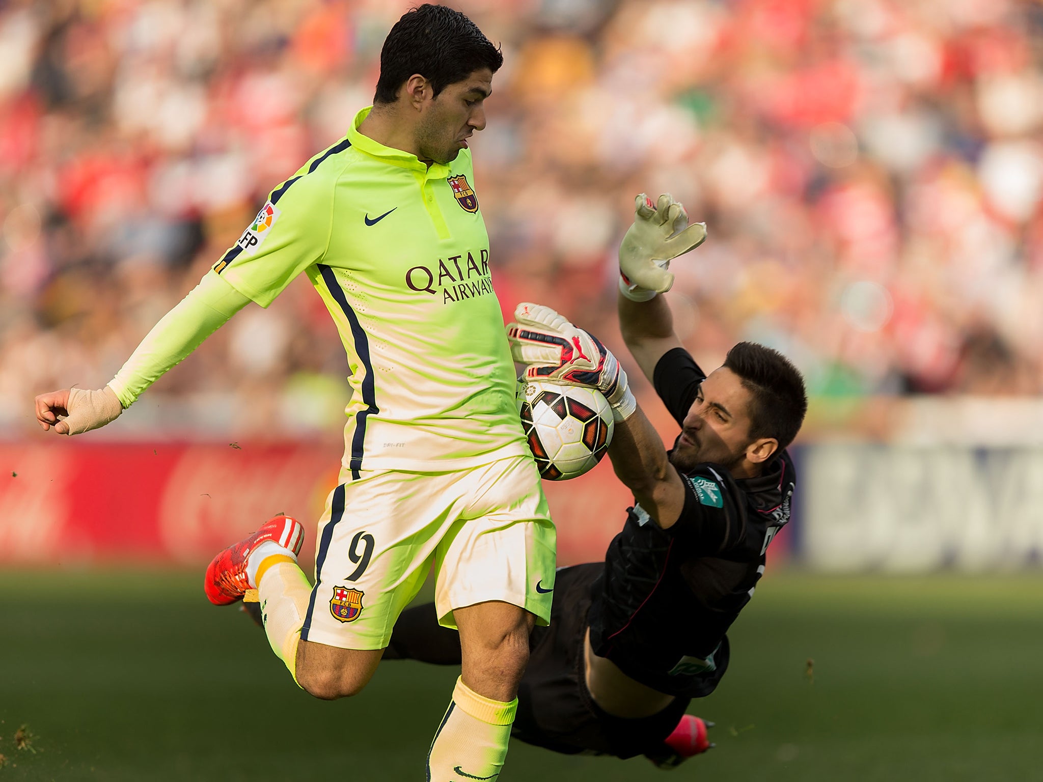 Luis Suarez competes for the ball with goalkeeper Oier Olazabal of Granada