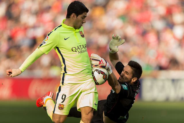 Luis Suarez competes for the ball with goalkeeper Oier Olazabal of Granada 