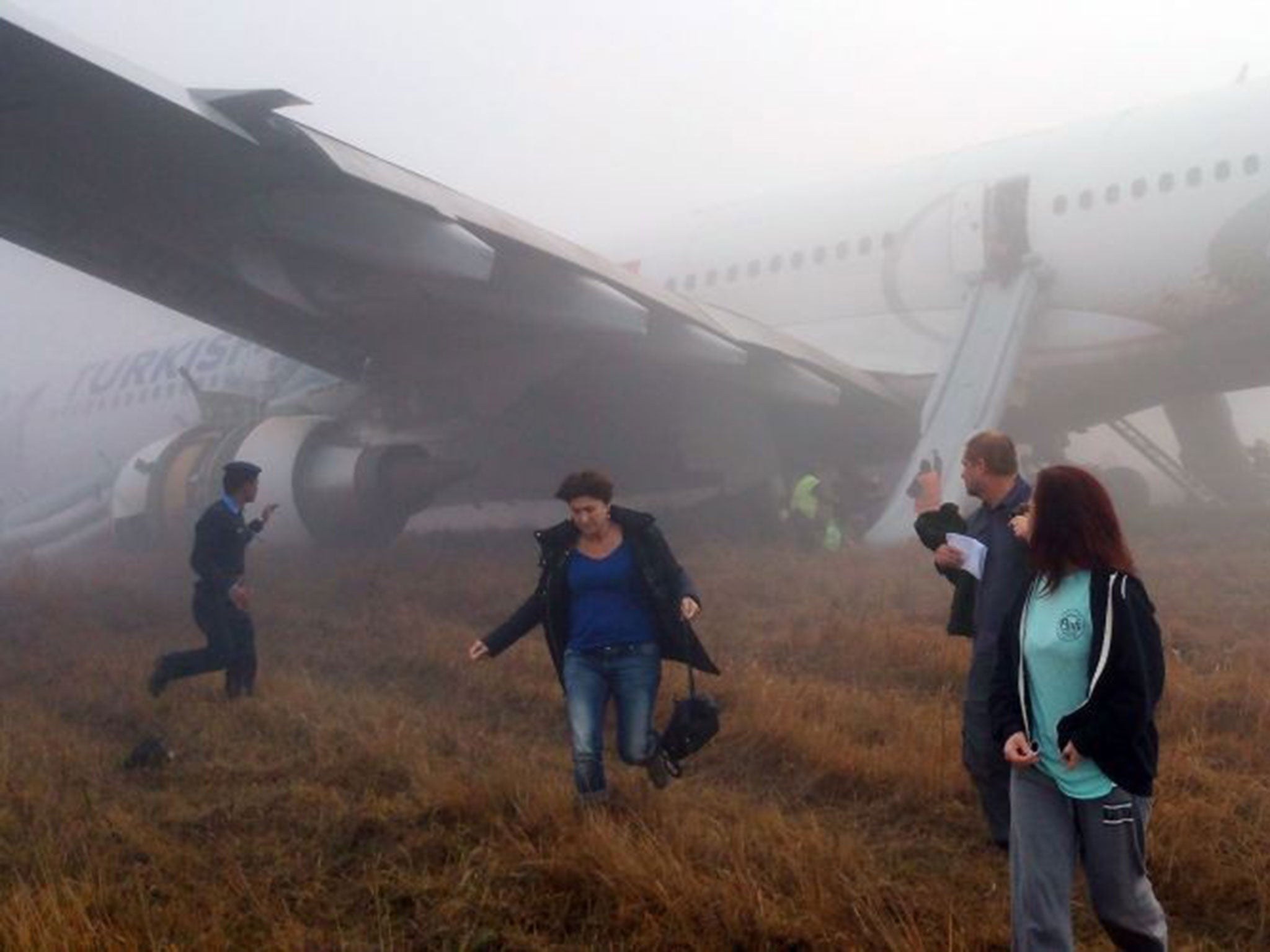 Passengers walk away from a Turkish Airlines plane after it skidded off the runway while landing at Kathmandu airport