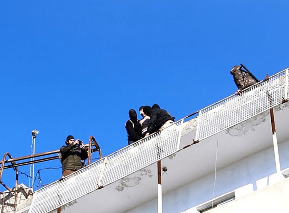 Isis militants stand with the blindfolded victim at the top of the tower (supplied by SOHR)