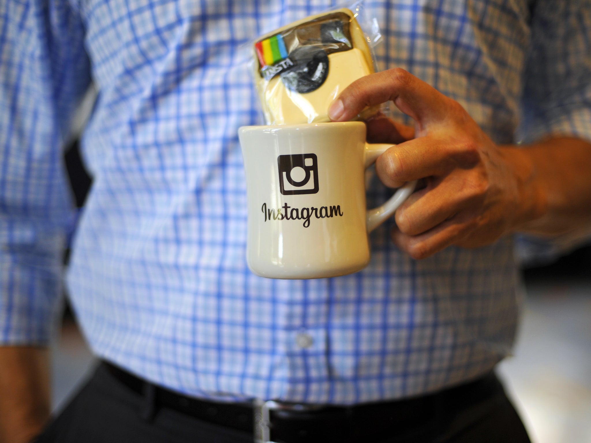 An employee holds a cup with the Instagram logo at Facebook's corporate headquarters during a media event
