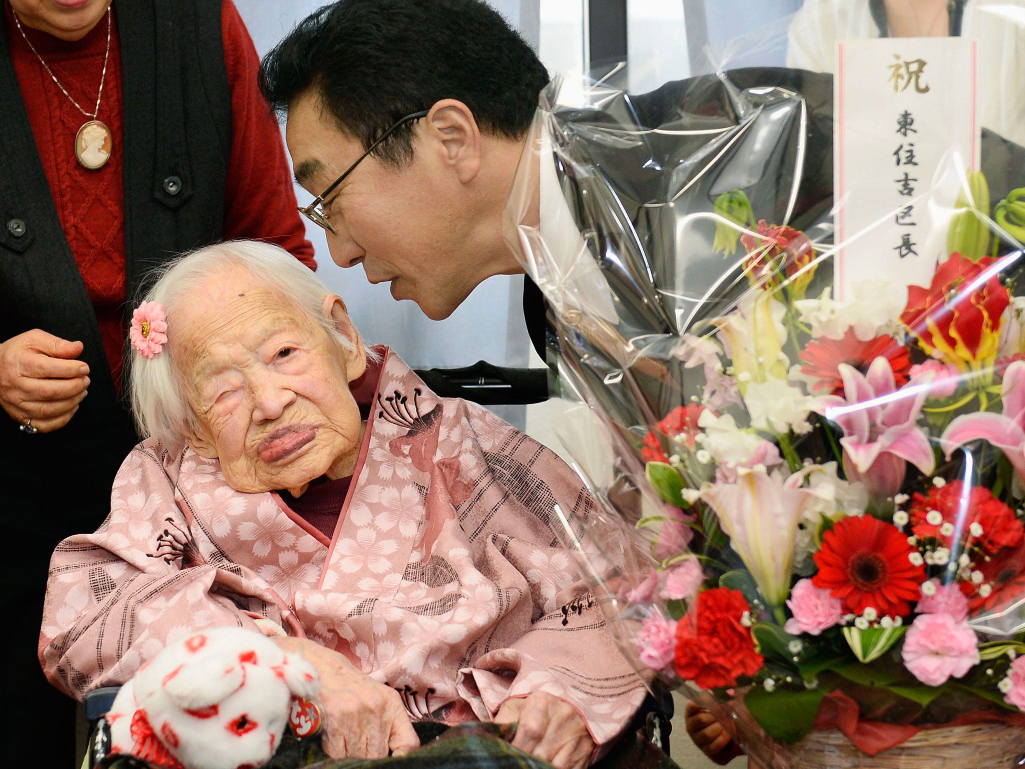 Japanese Misao Okawa, the world's oldest living person, is celebrated by Takehiro Ogura (R), mayor of Osaka's Higashi-Sumiyoshi Ward, at an elder care facility in Osaka, western Japan, the day before her 117th birthday