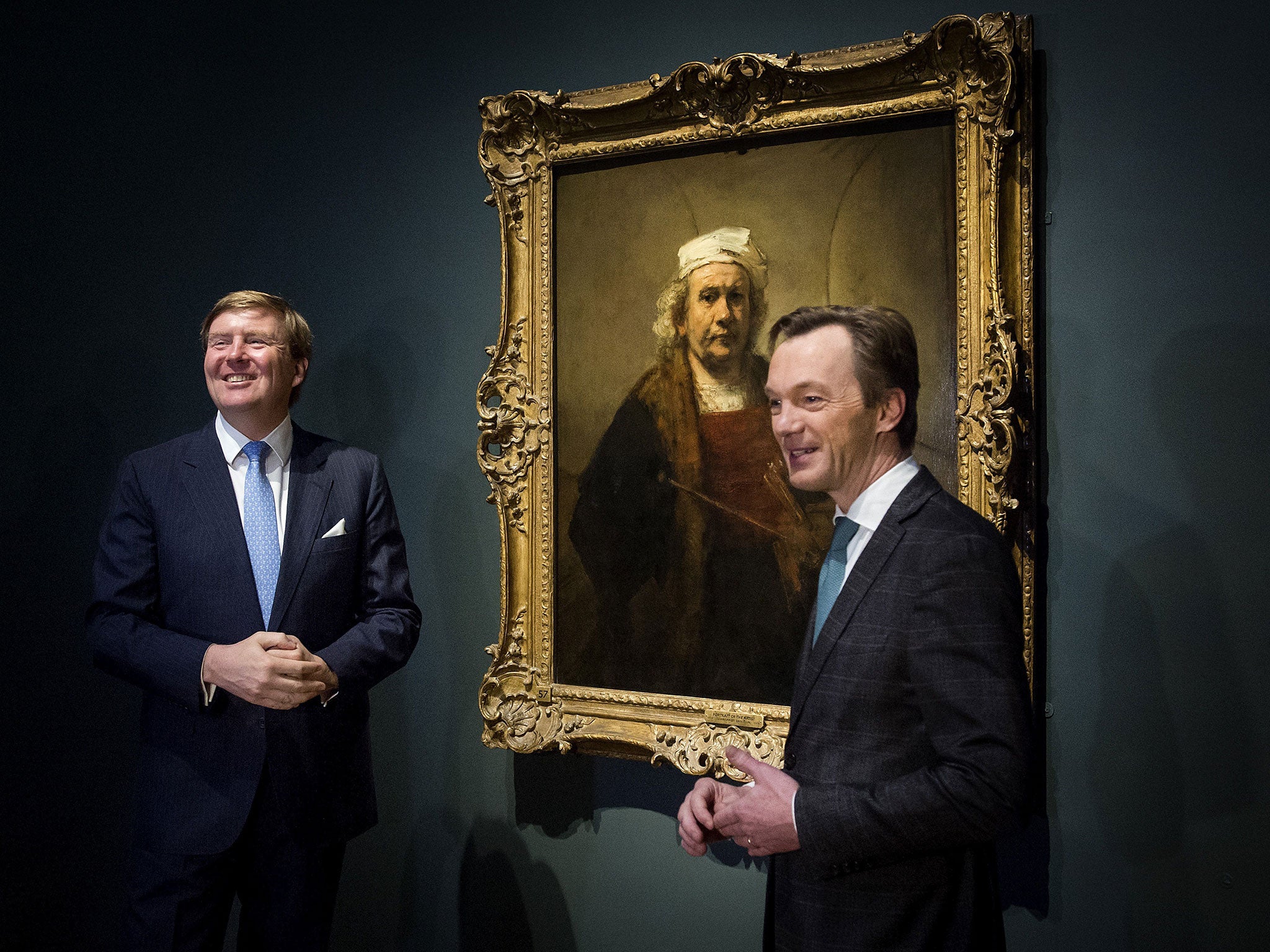 Dutch King Willem Alexander (L) and museum director Wim Pijbes (R) pose beside a painting entitled 'Self Portrait with two circles' by Dutch master Rembrandt during the official opening of the new exhibition of late works by Rembrandt at the Rijksmuseum in Amsterdam on February 12, 2015.