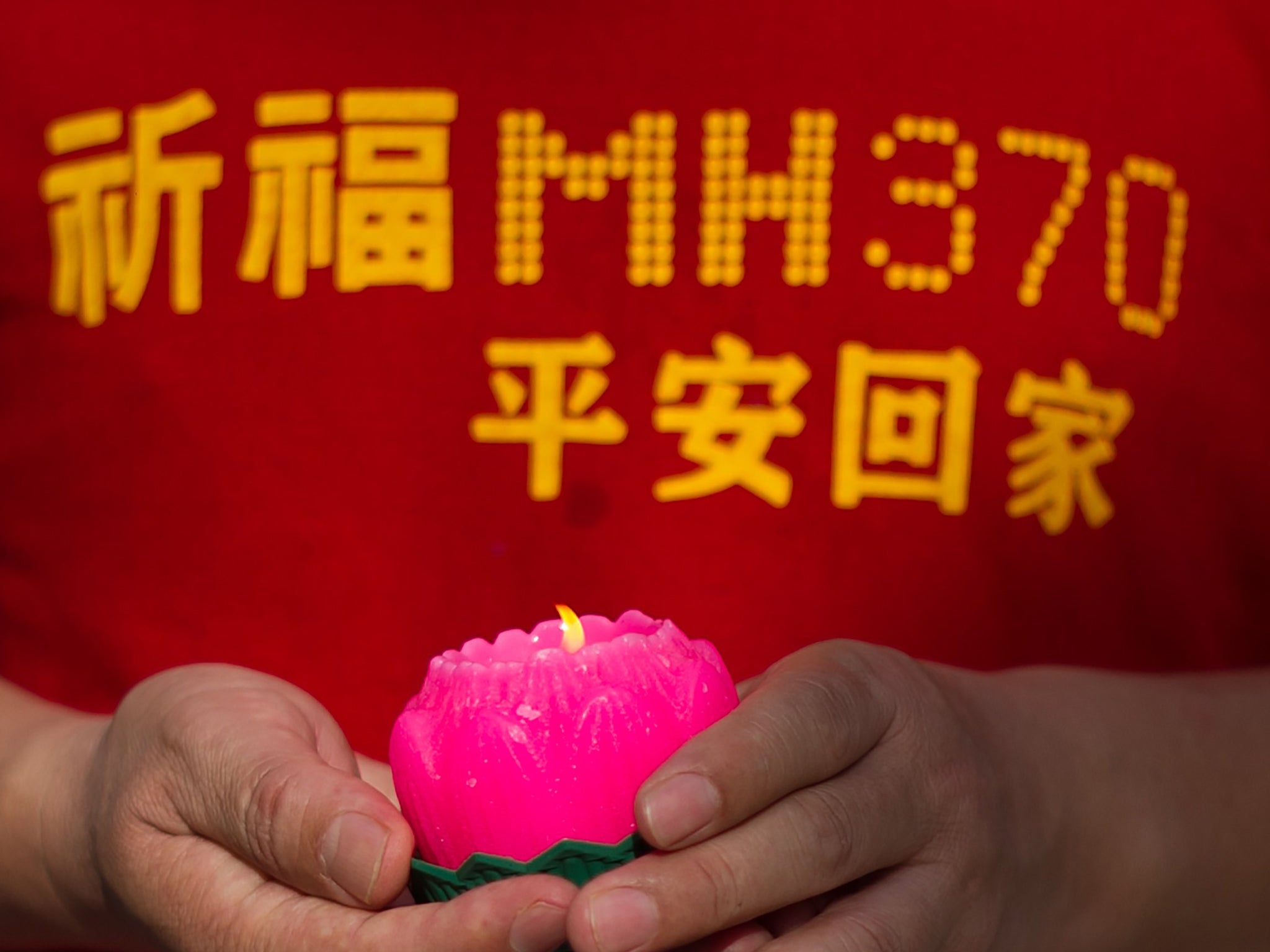 A relative of one of the Chinese passengers from the missing Malaysia Airlines flight MH370 holds a candle