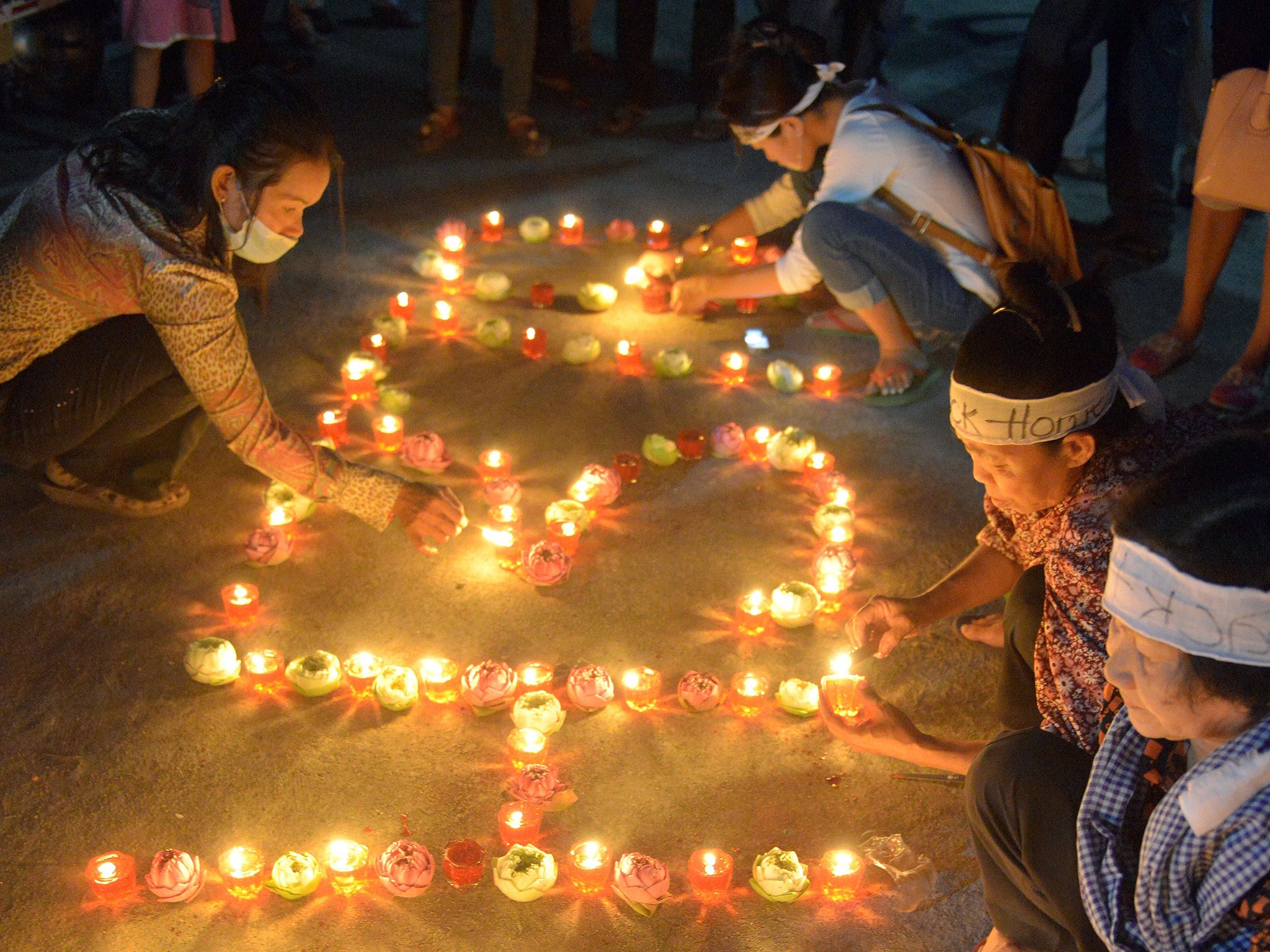 Cambodian residents of a community light candles as they pray for the missing Malaysia Airlines flight MH370