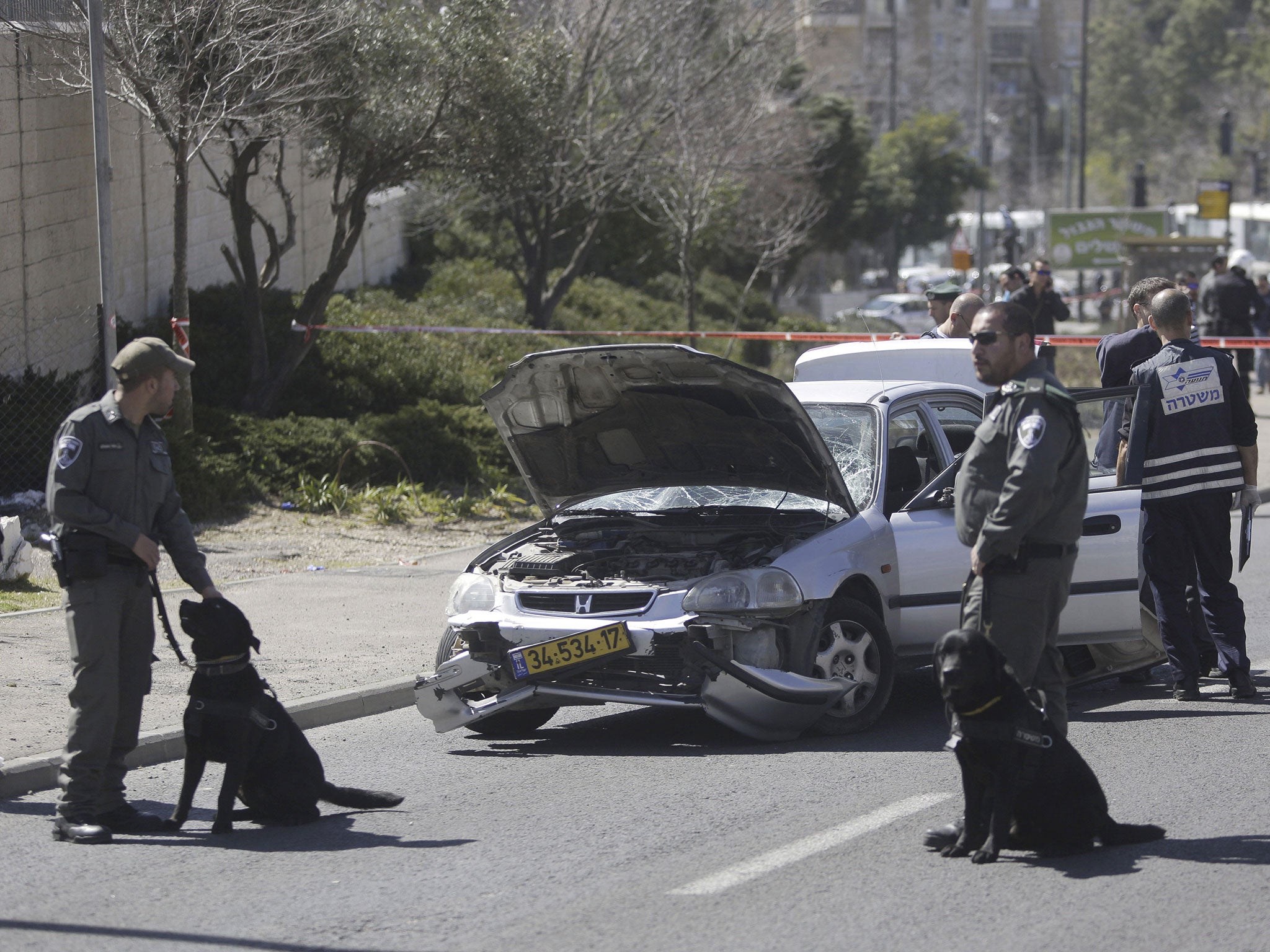 Israeli police stand next to a damaged car