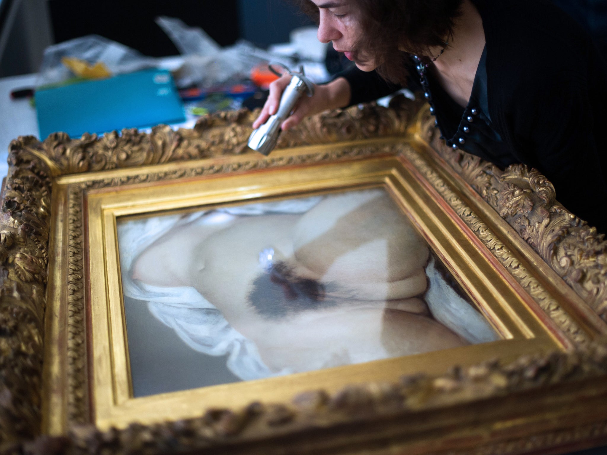 A woman examines the Gustave Courbet's canvas 'L'origine du monde' (The origin of the world) before its installation at the Courbet museum on June 3, 2014, in Ornans, eastern France