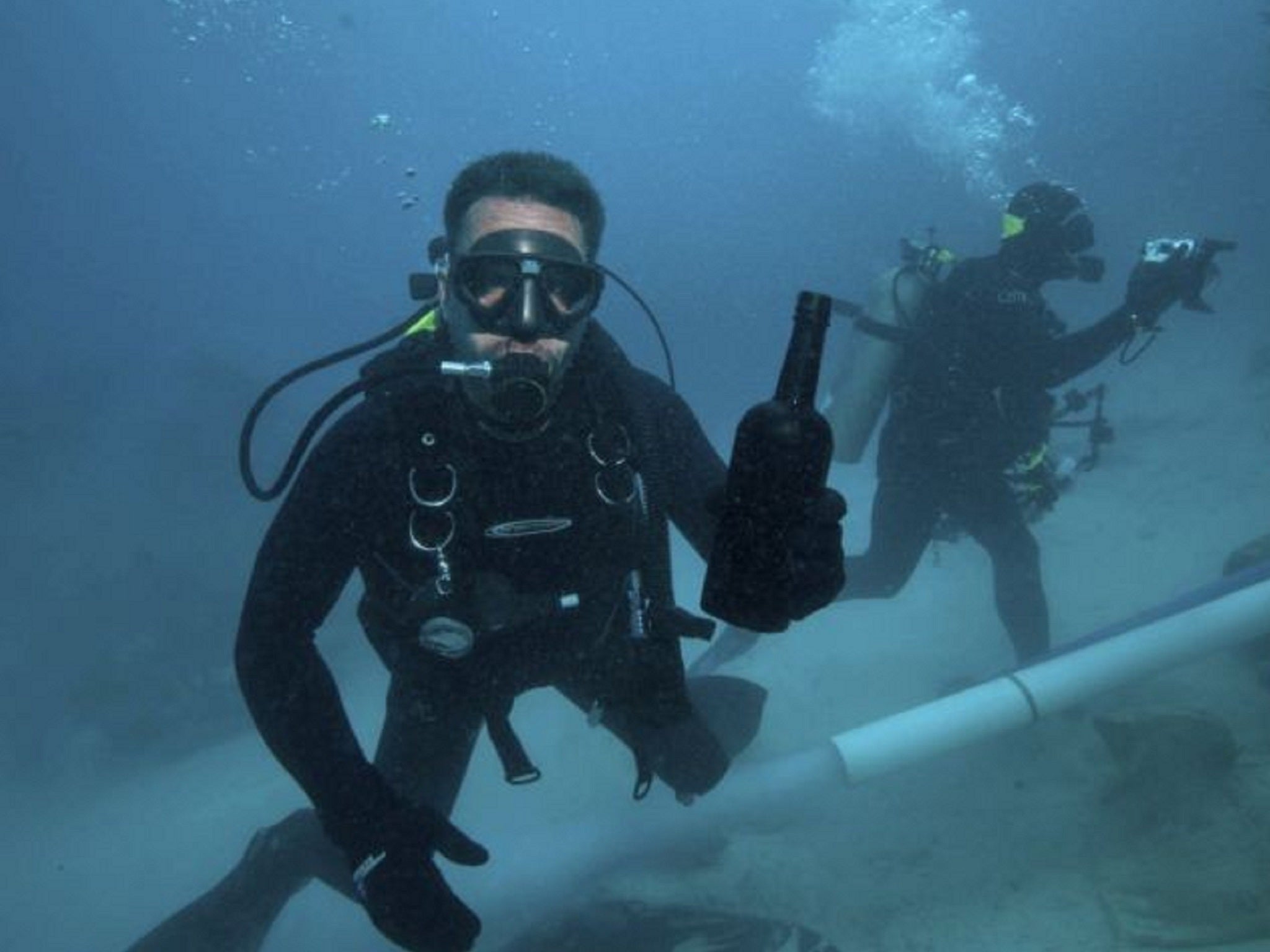 A diver holds the bottle from the Civil War ship Mary-Celestia in 2011