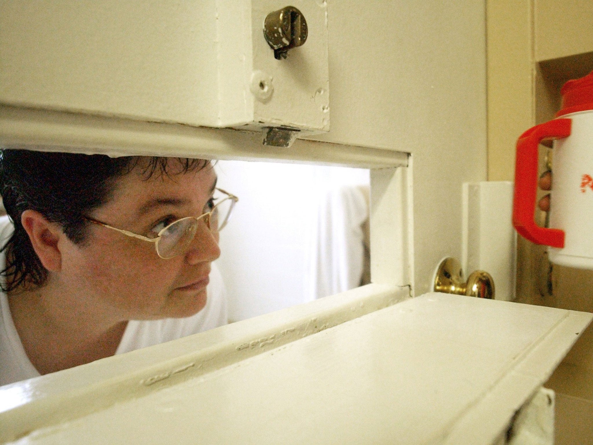 Kelly Gissendaner, the only woman on Georgia's death row, peers through the slot in her cell door as a guard brings her a cup of ice at Metro State Prison in Atlanta