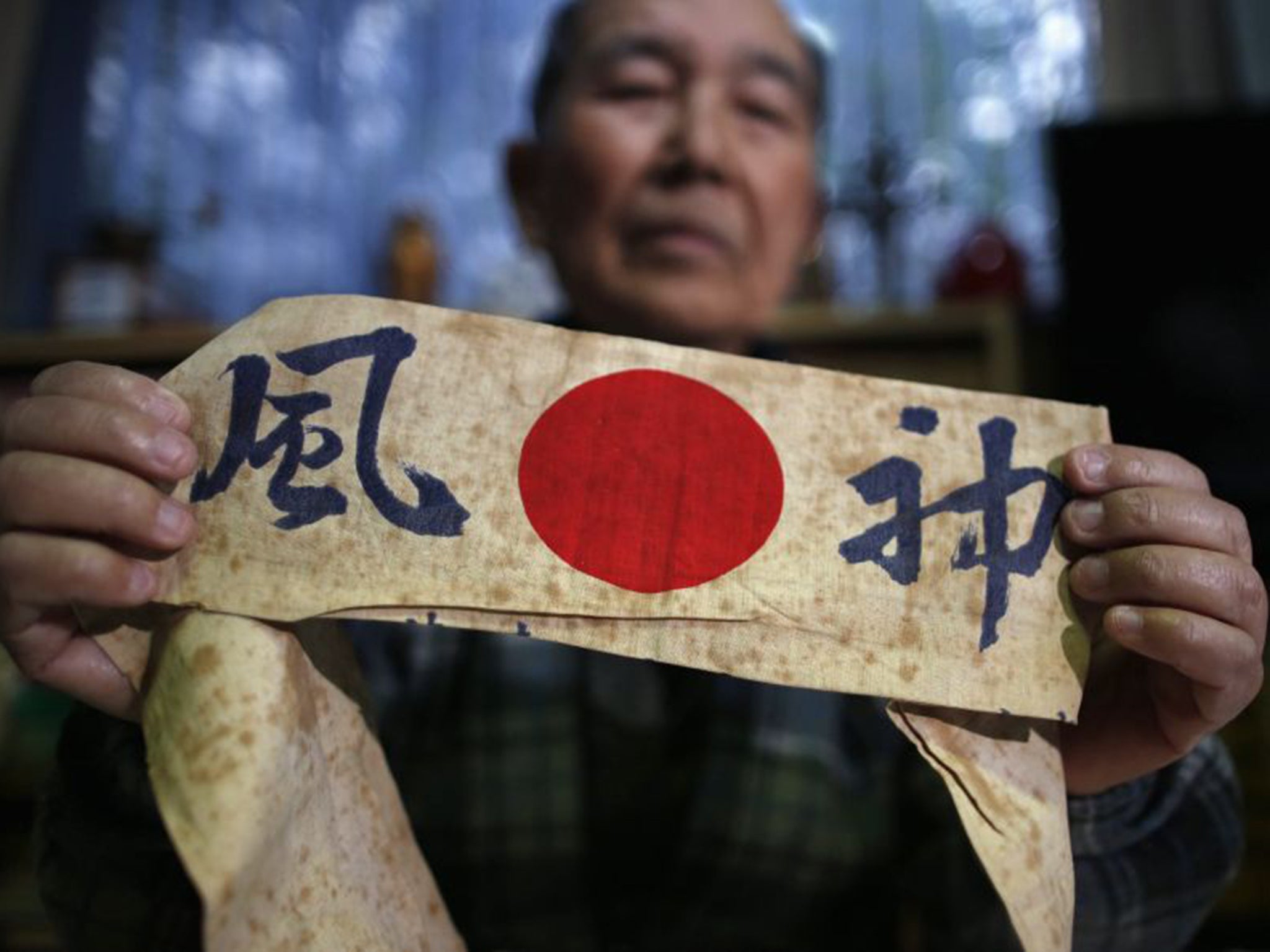 Katsumoto Saotome, 82, a survivor of the raids in 1945, holds a headband with the word ‘Kamikaze’ written on it