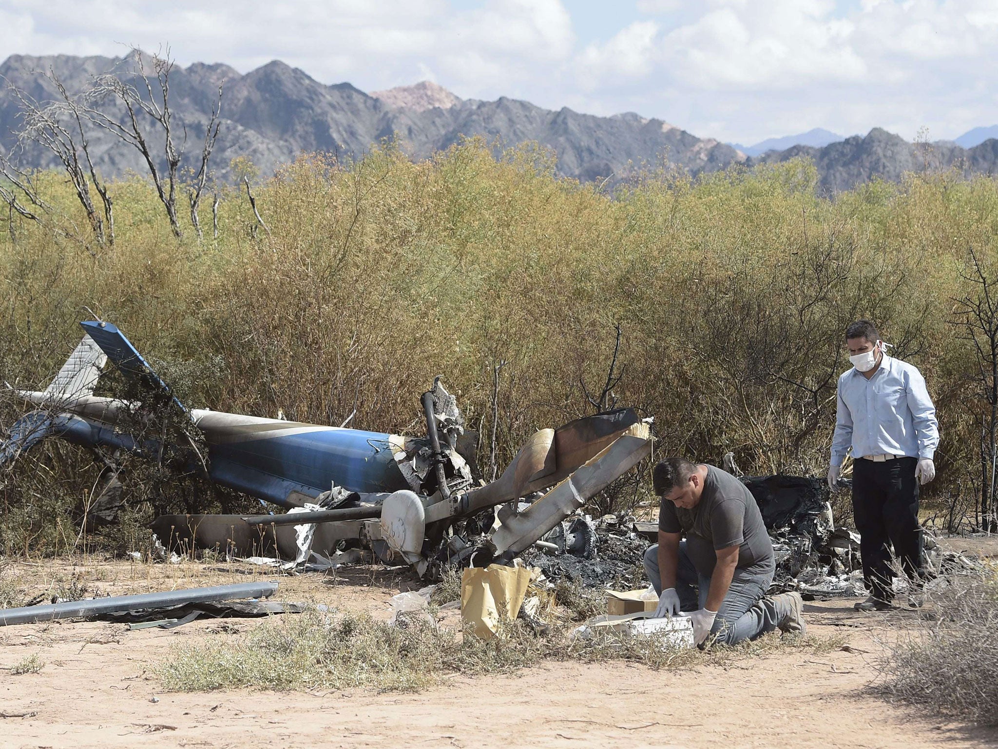 Men work amid the wreckage of two helicopters which collided mid-air near Villa Castelli