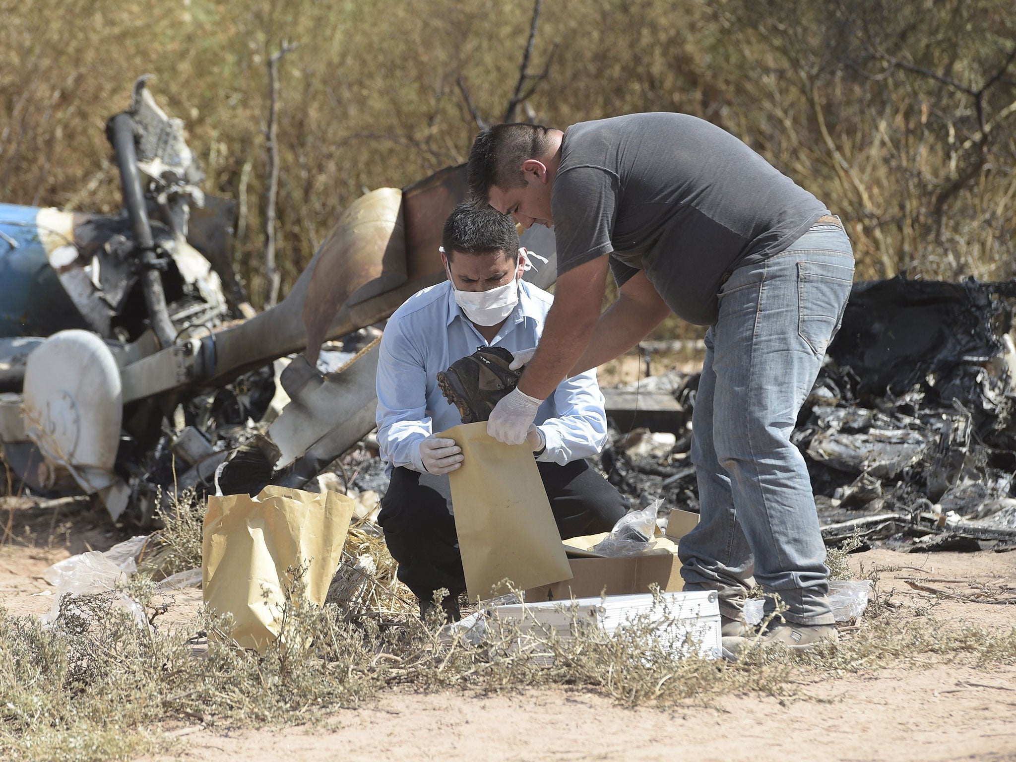 Men work amid the wreckage of two helicopters which collided mid-air near Villa Castelli