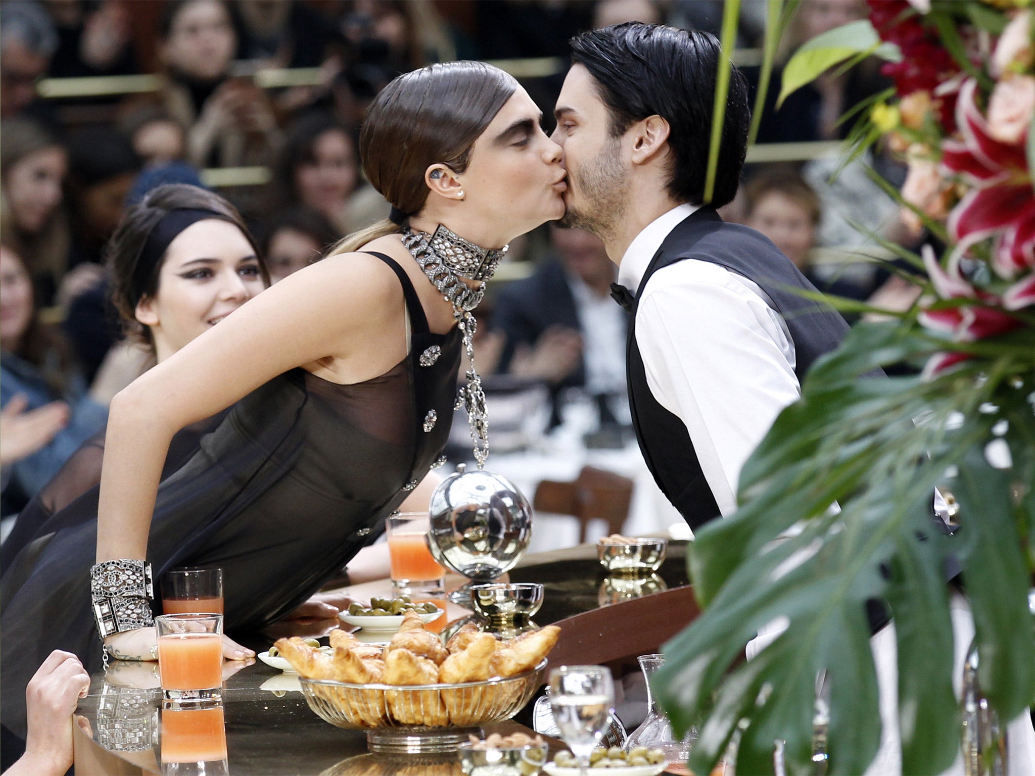 Cara Delevingne works Karl Lagerfeld’s brasserie theme by kissing a waiter