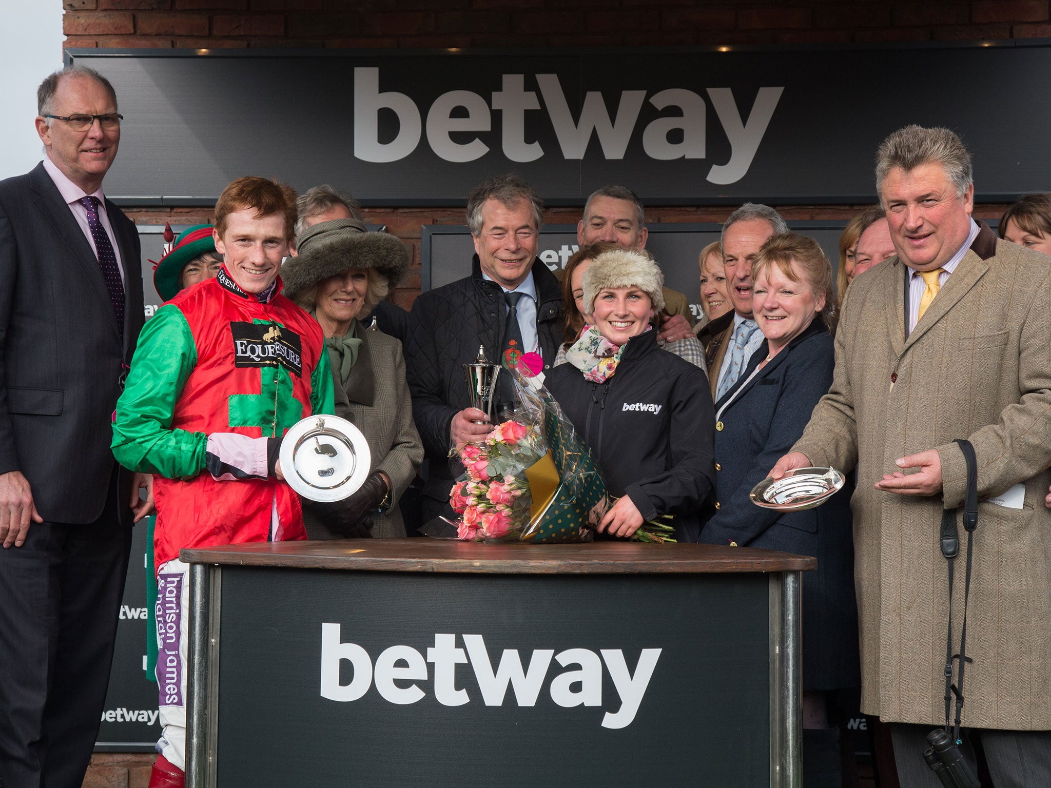 Camilla, Duchess of Cornwall makes a presentation to the owners jockey Sam Twiston-Davies and trainer Paul Nicholls (far left in yellow tie) of the winning horse in the Betway Queen Mother Champion Steeple Chase