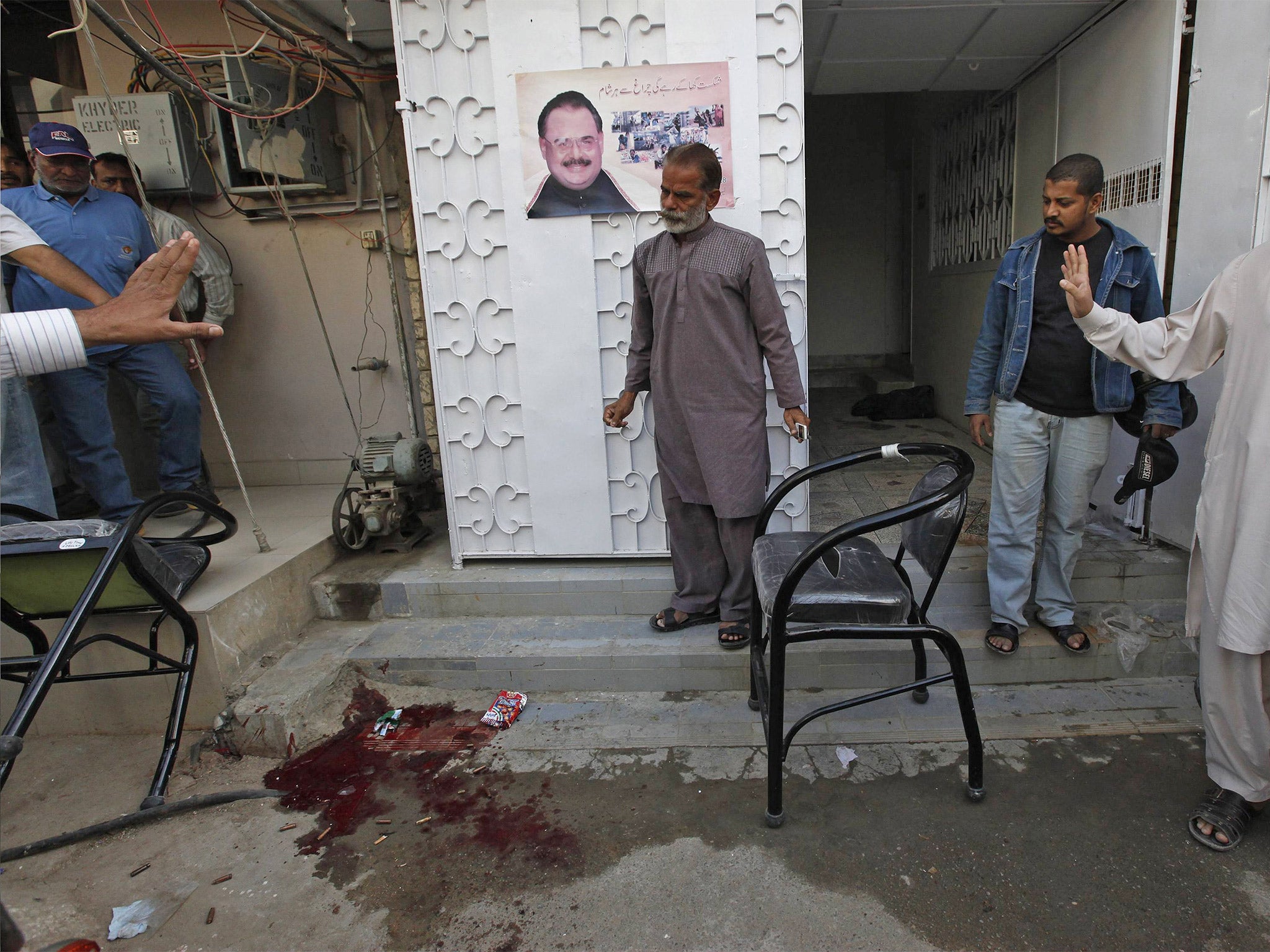 Residents gather beside blood stains on ground outside the MQM office