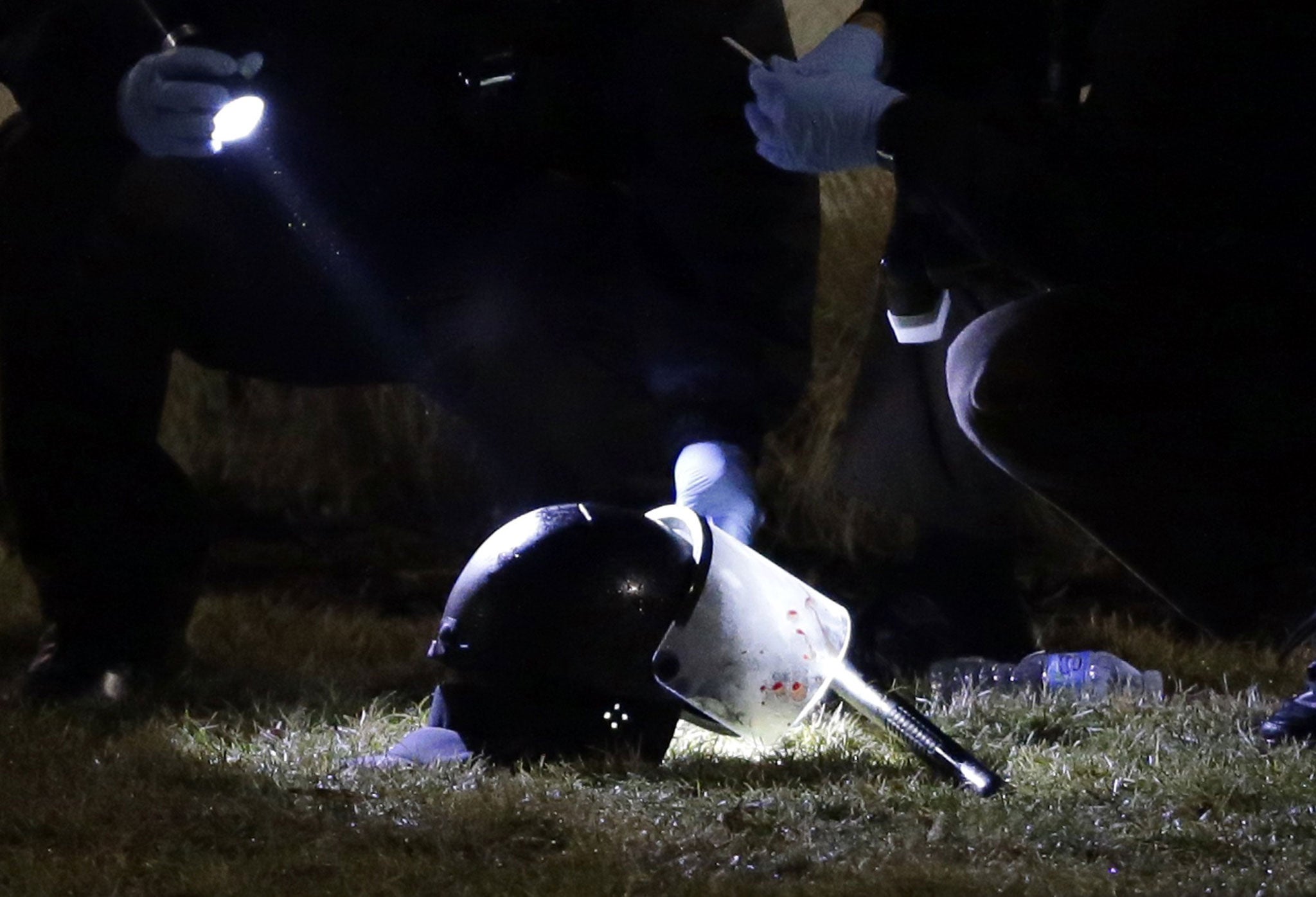 Police examine a blood-stained helmet after the shooting in Ferguson, Missouri