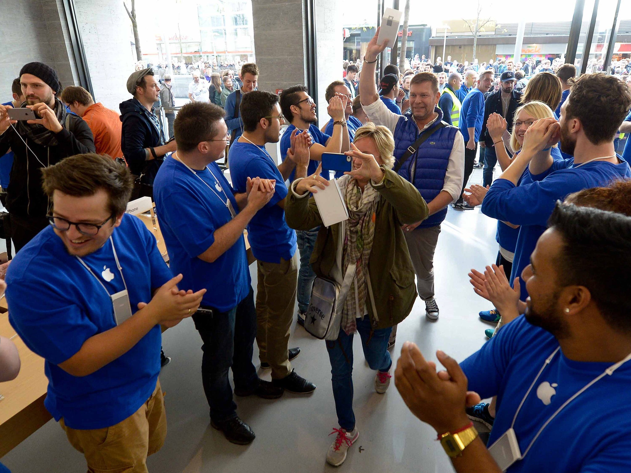 Apple employees greet costumers on the opening of an Apple Store in Hanover, central Germany on September 27, 2014