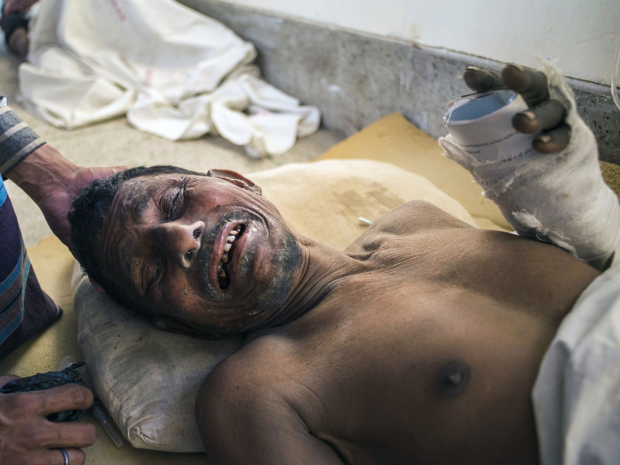 A Bangladeshi survivor of the collapse of a partly-built cement factory in Mongla, lies on the floor of a hospital in Khulna on 12 March