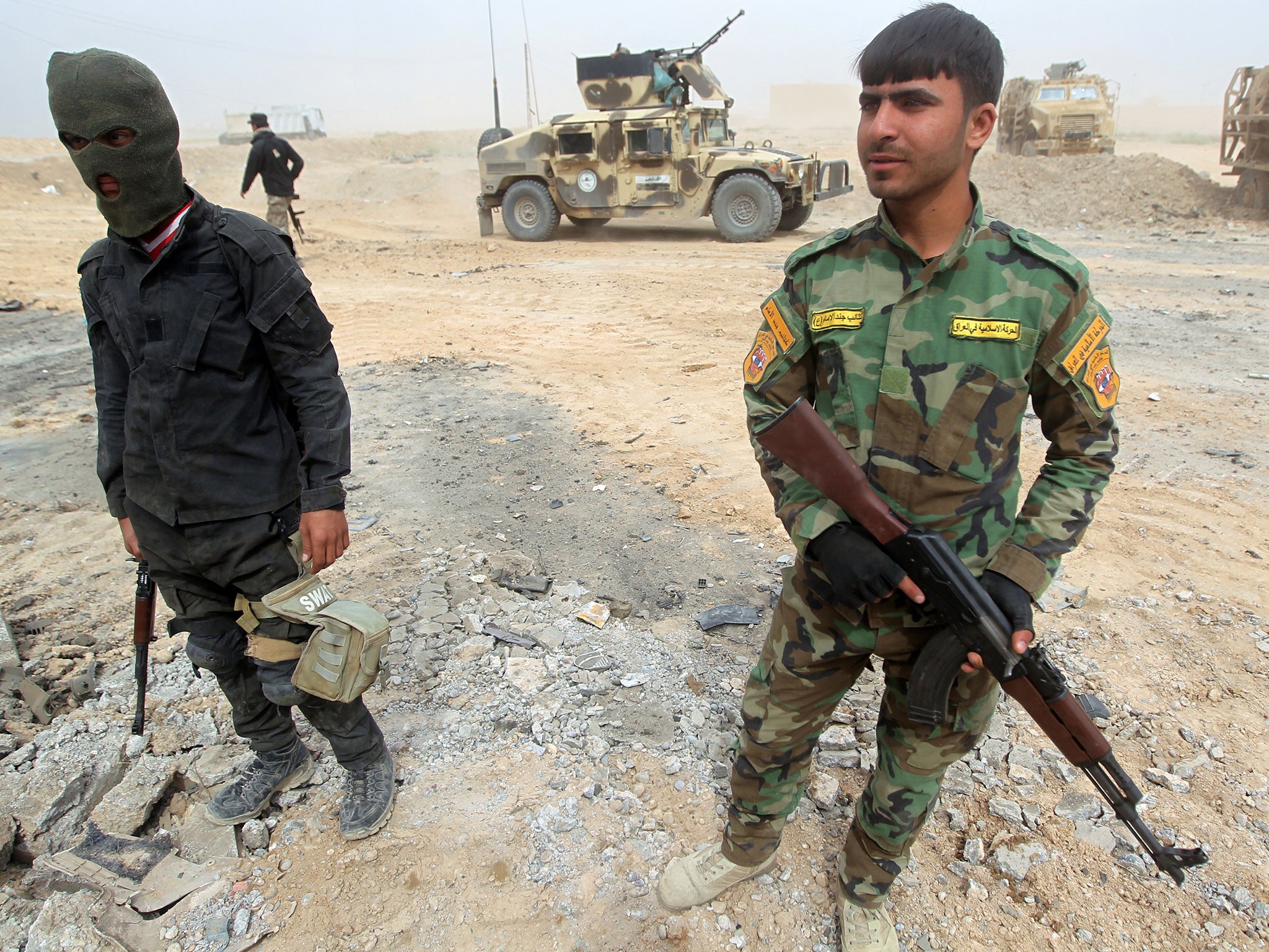 Shia fighters stand with their weapons in a suburb west of Tikrit