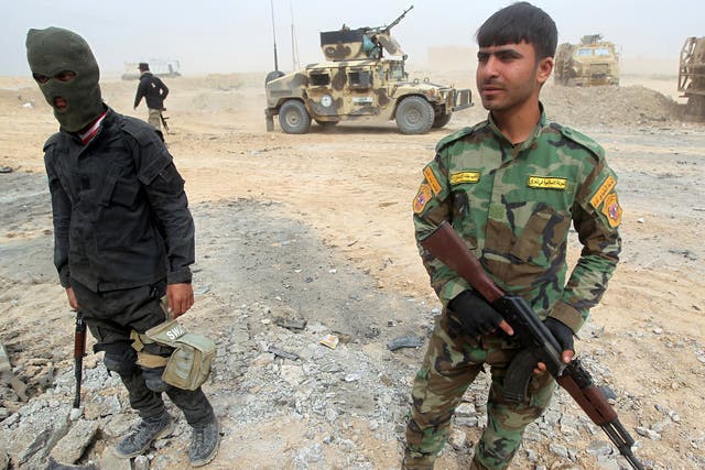 Shia fighters stand with their weapons in a suburb west of Tikrit