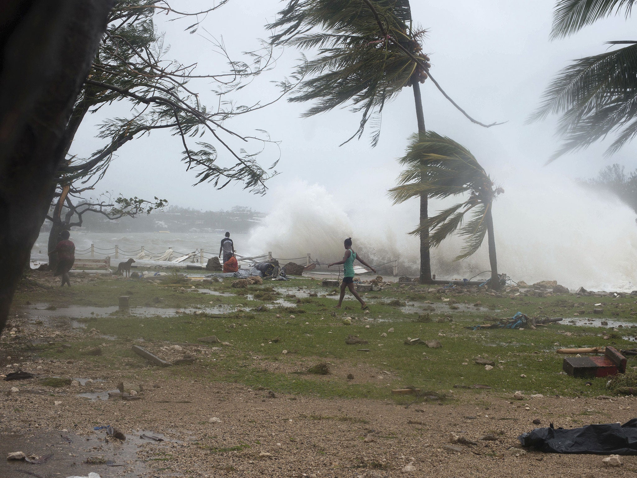 People walk along the shore where debris is scattered in Port Vila, Vanuatu on Saturday