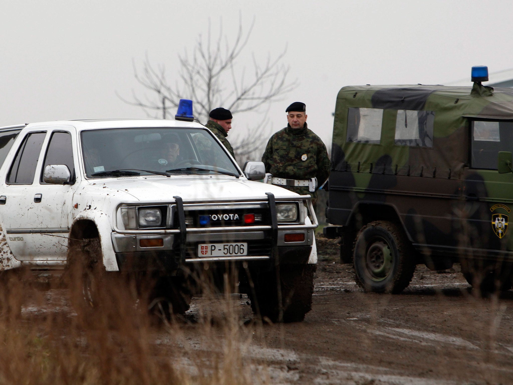 Military investigators seen near the site of a helicopter crash on the outskirts of Belgrade