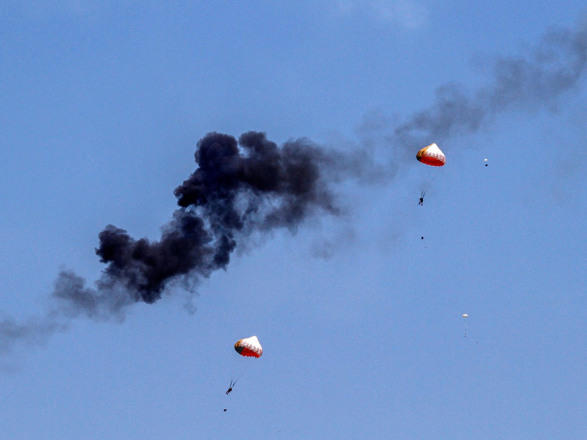 Two parachutes float in the air with smoke billowing after two Indonesian aerobatic plane crash in mid-air of Langkawi, Malaysia