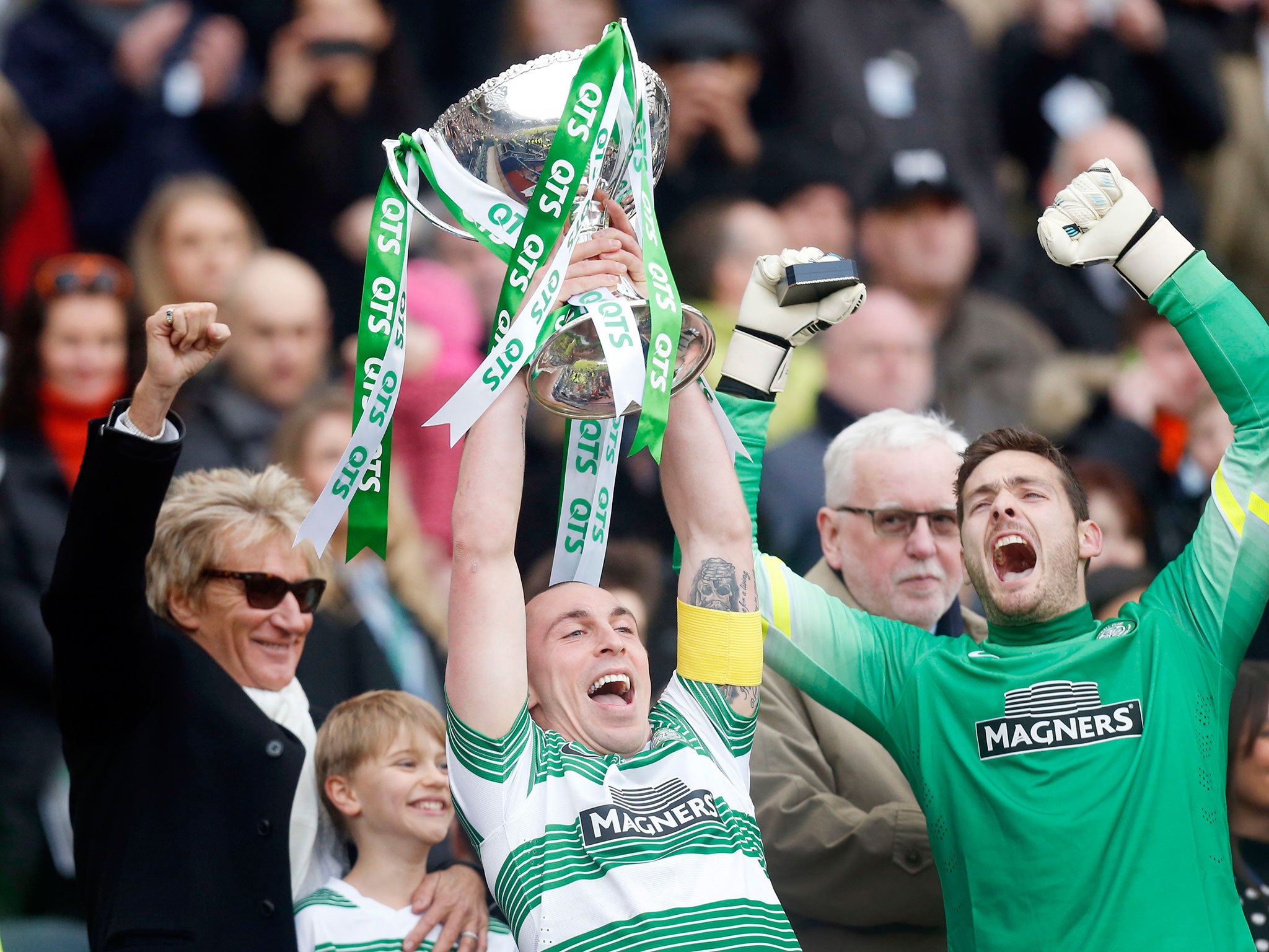 Scott Brown holds aloft the Scottish League Cup – watched by Craig Gordon, right, and rock star Rod Stewart, left