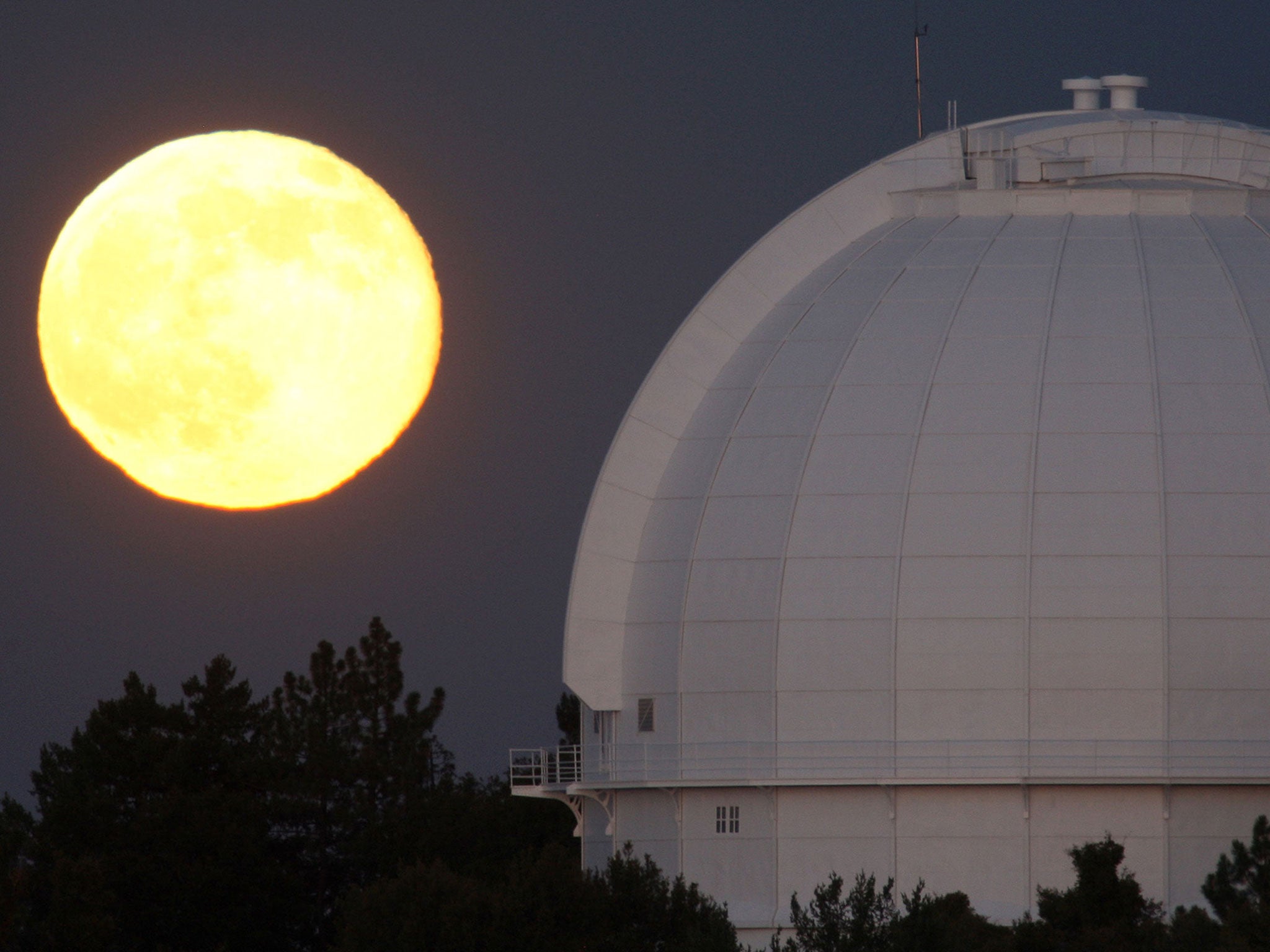 The golden globe rises behind the historic Mount Wilson Observatory on in the Angeles National Forest, northeast of Los Angeles, California