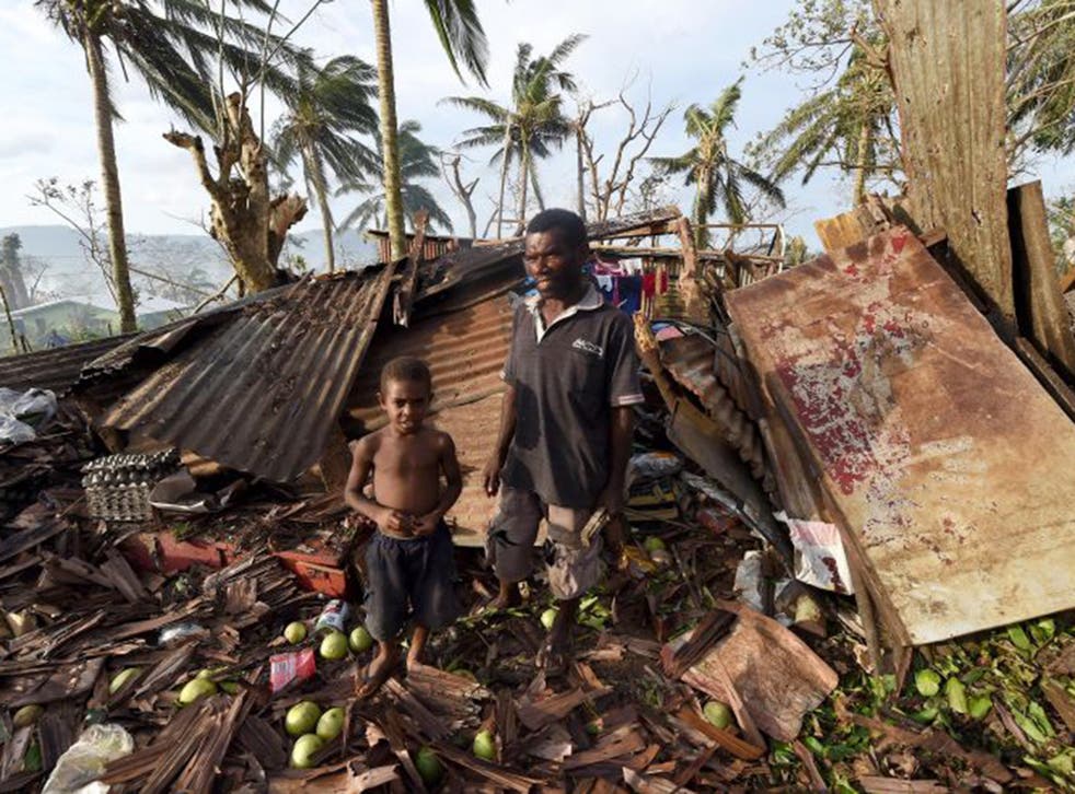 Vanuatu residents stand in the wreckage of their home