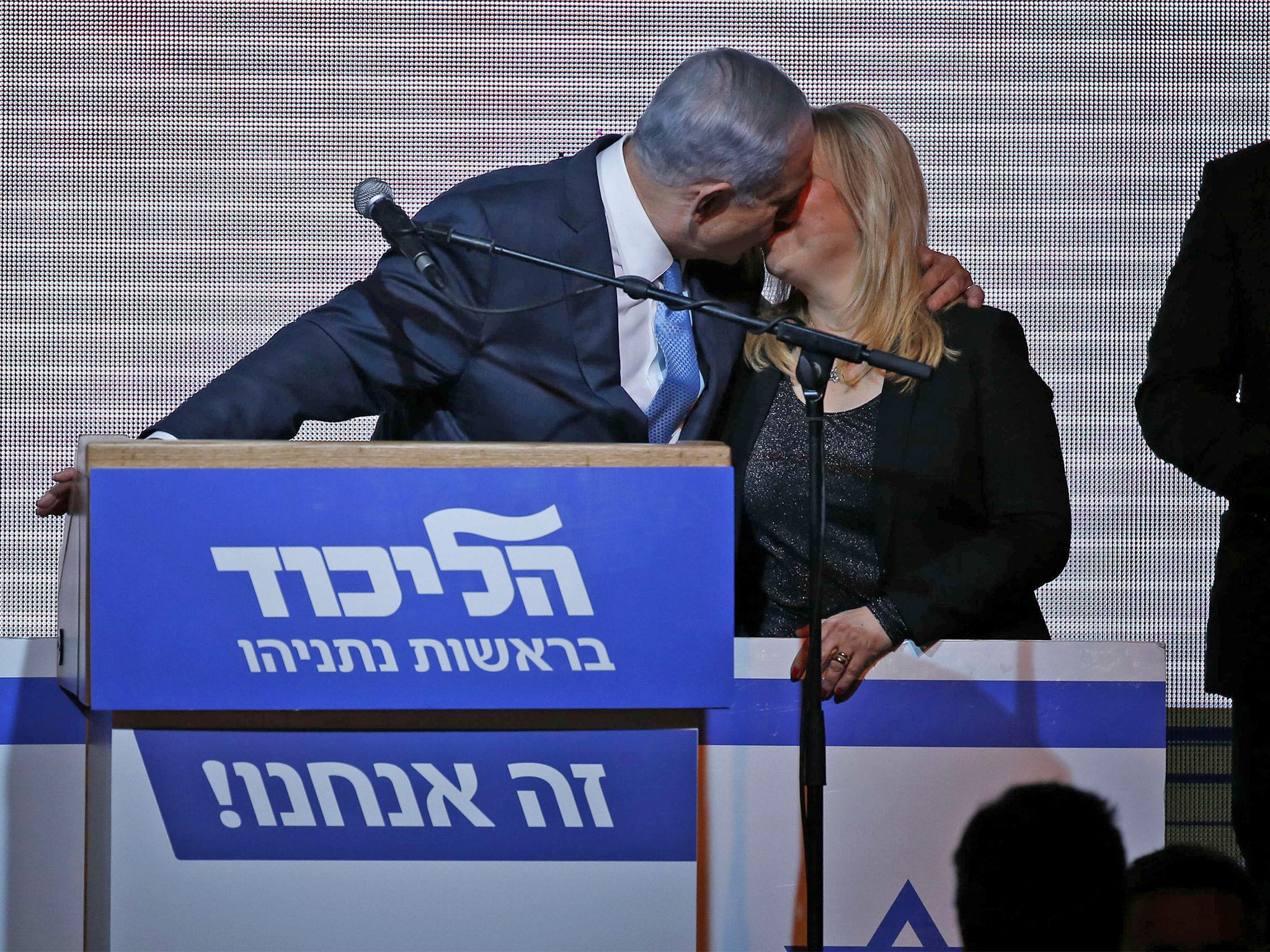 Israeli Prime Minister Benjamin Netanyahu kisses his wife Sara as he reacts to exit poll figures, in Tel Aviv