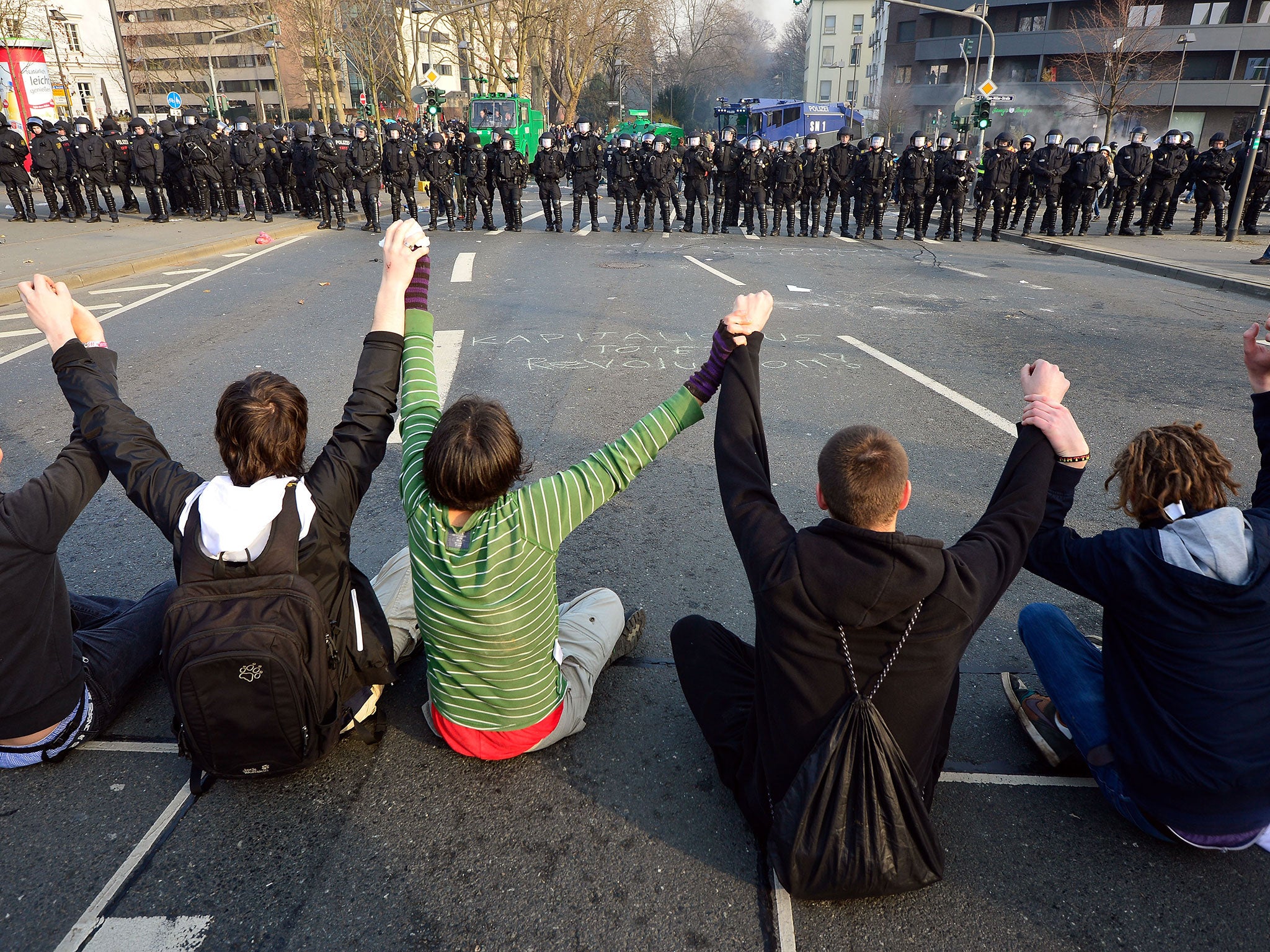 Activists sit and hold hands in front of a police cordon